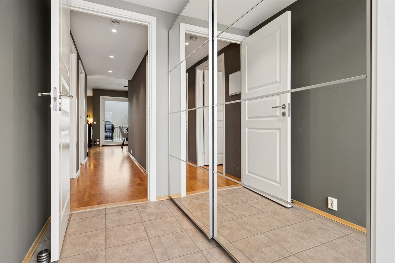 Entréen har fliser med praktisk gulvvarme som tar godt imot våte sko på regnfulle dager. Skyvedørsgarderoben med speilfronter gir smart oppbevaring, virker romforstørrende og gjør det enkelt å sjekke antrekket før du går ut Galleribilde