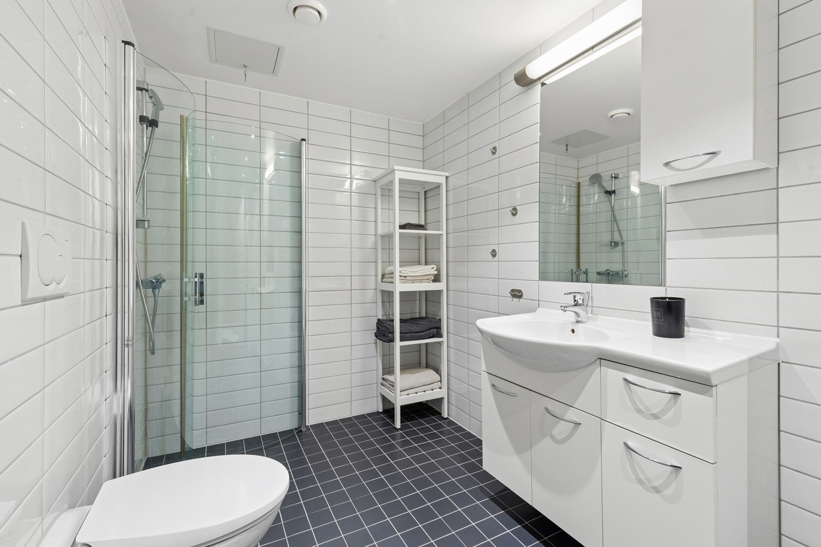 Badet er et romslig modulbad med flislagte overflater og dusjhjørne med buede dører Galleribilde