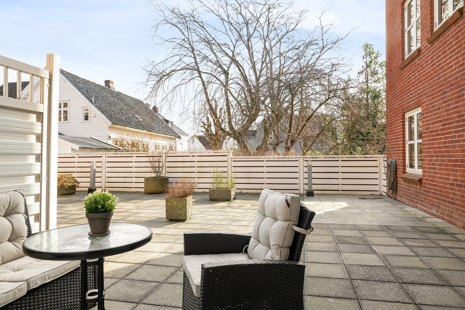 Her har man sør-vendt uteplass med god sol. Uteplassen har i dag levegger for skjerming Galleribilde