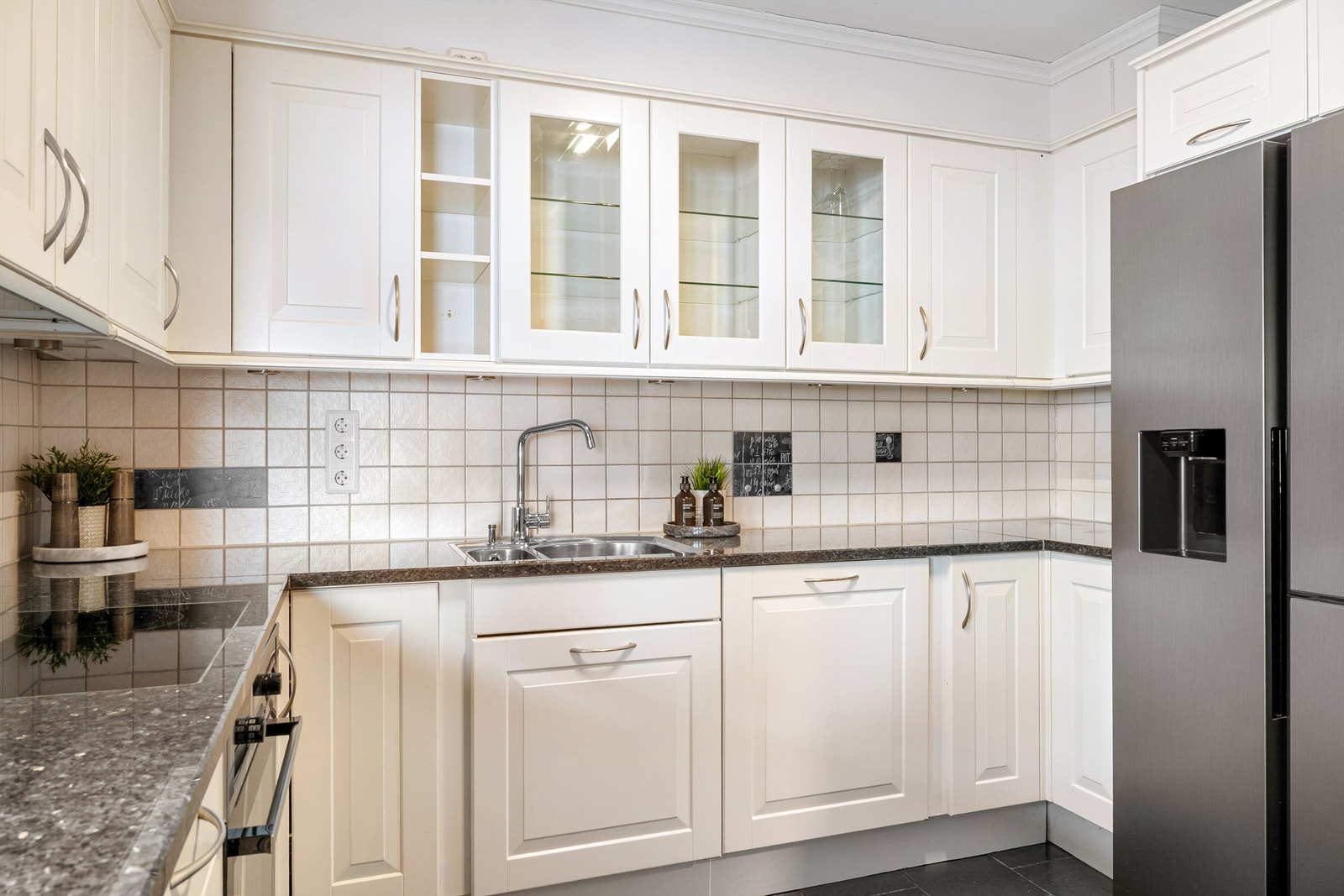 Tidløs innredning med hvite profilerte fronter, benkeplate i stein og lyse fliser Galleribilde