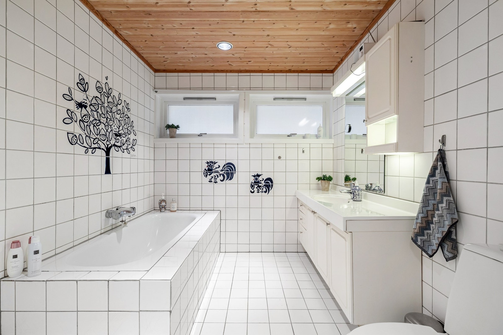 Flislagt baderom fra byggeår med gulvvarme. I tillegg til toalett, servant og badekar er det plassert et dusjhjørne ved enden av badekaret Galleribilde