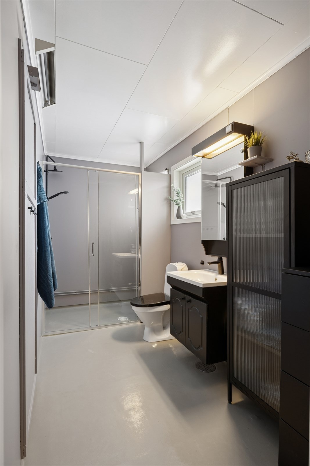 Badet har vinylbelegg på gulvet, baderomsplater på veggene og himlingsplater i taket. Stråleovn som oppvarming og naturlig ventilasjon. Galleribilde