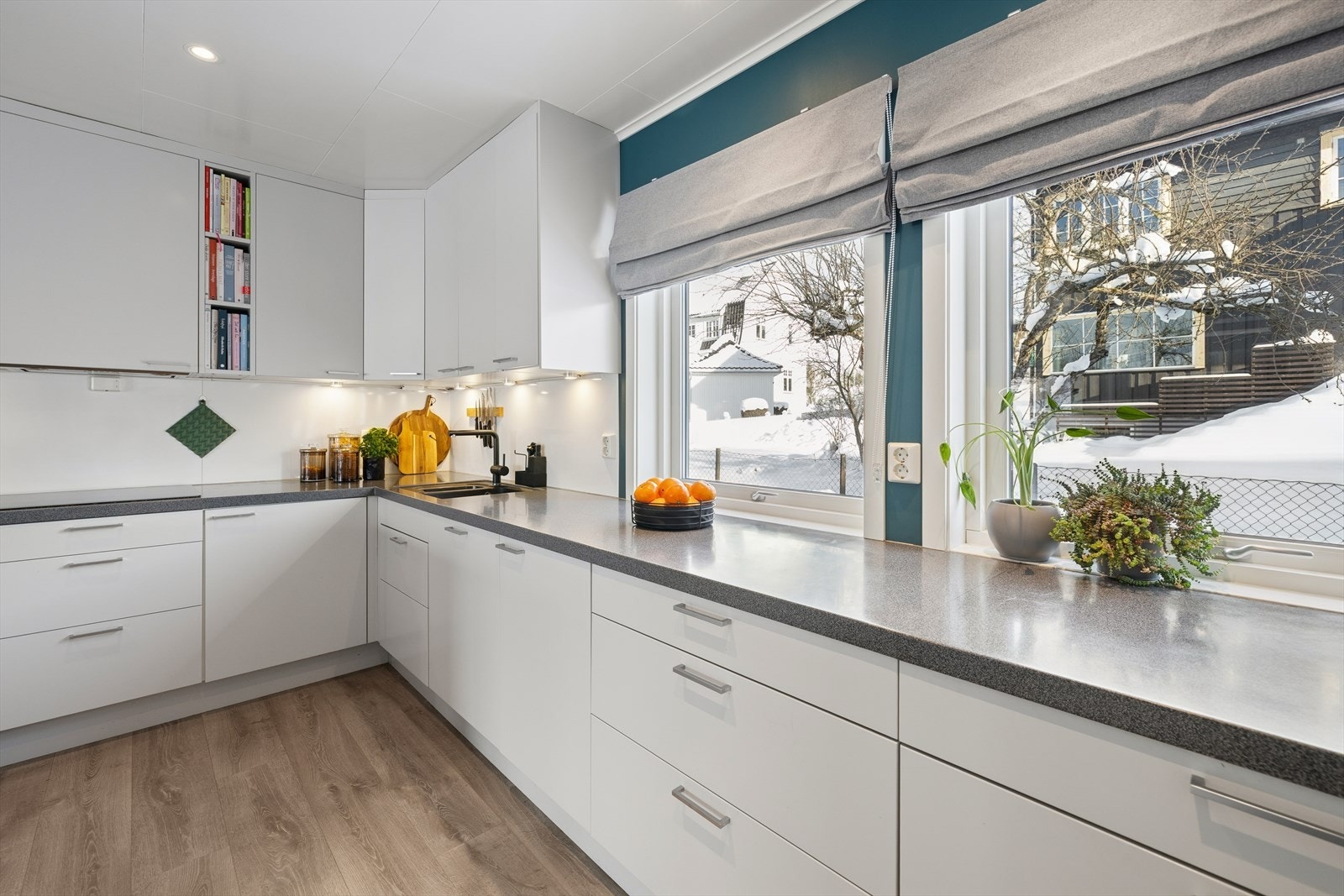 Det er belysning under overskapene og hvite plater i benkeryggen. Galleribilde