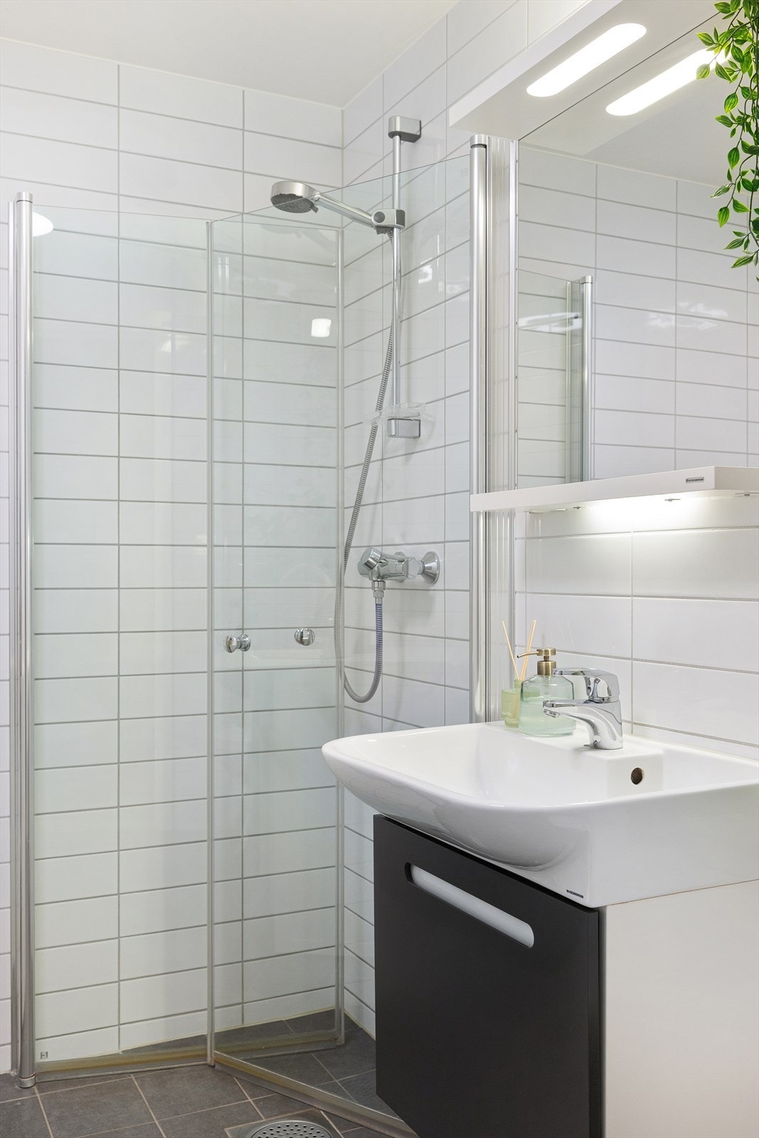 Romslig dusjhjørne med glassdører og veggmontert dusjarmatur. Galleribilde