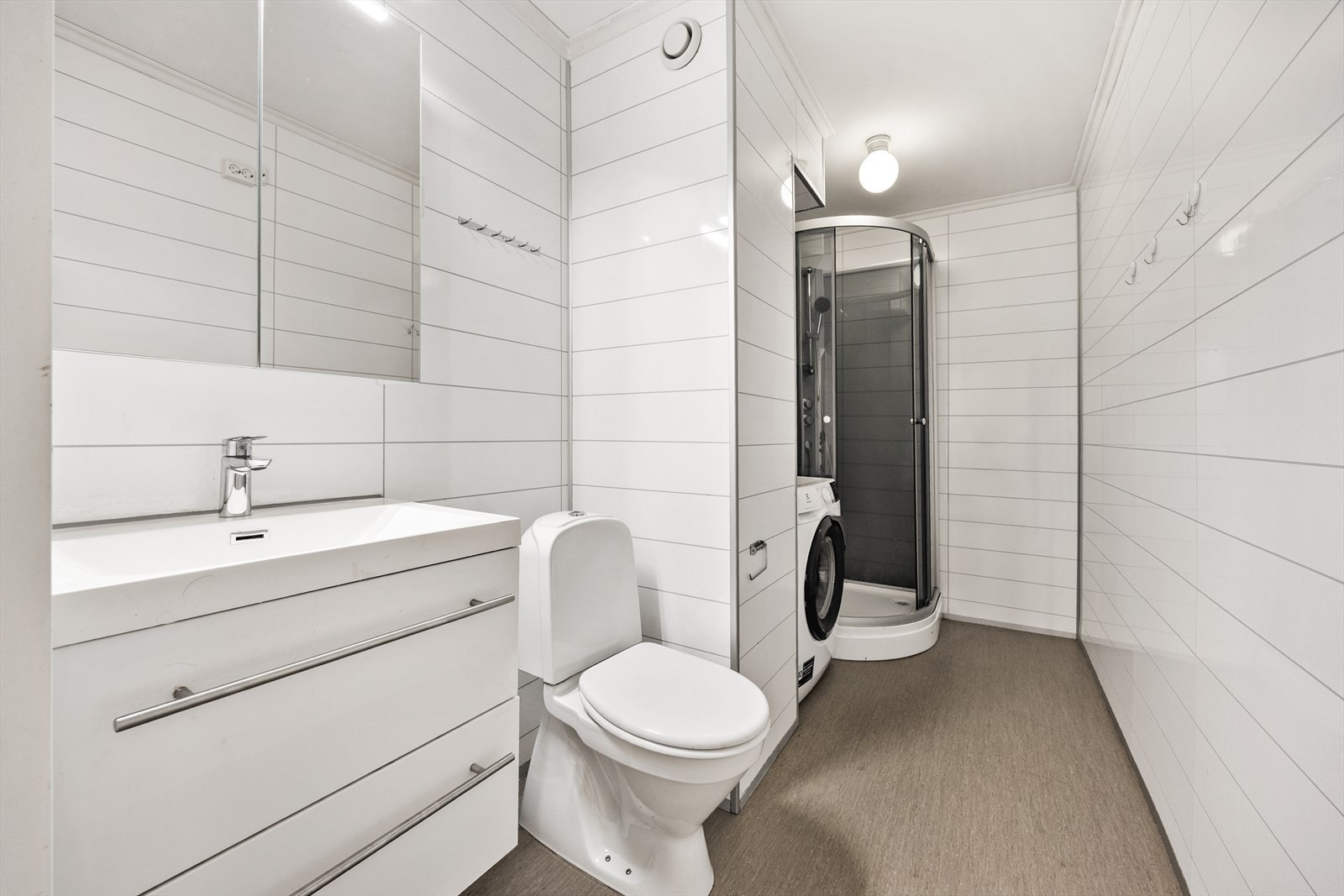 Badet har vegger med baderomsplater og praktisk vinylbelegg på gulvet. Galleribilde