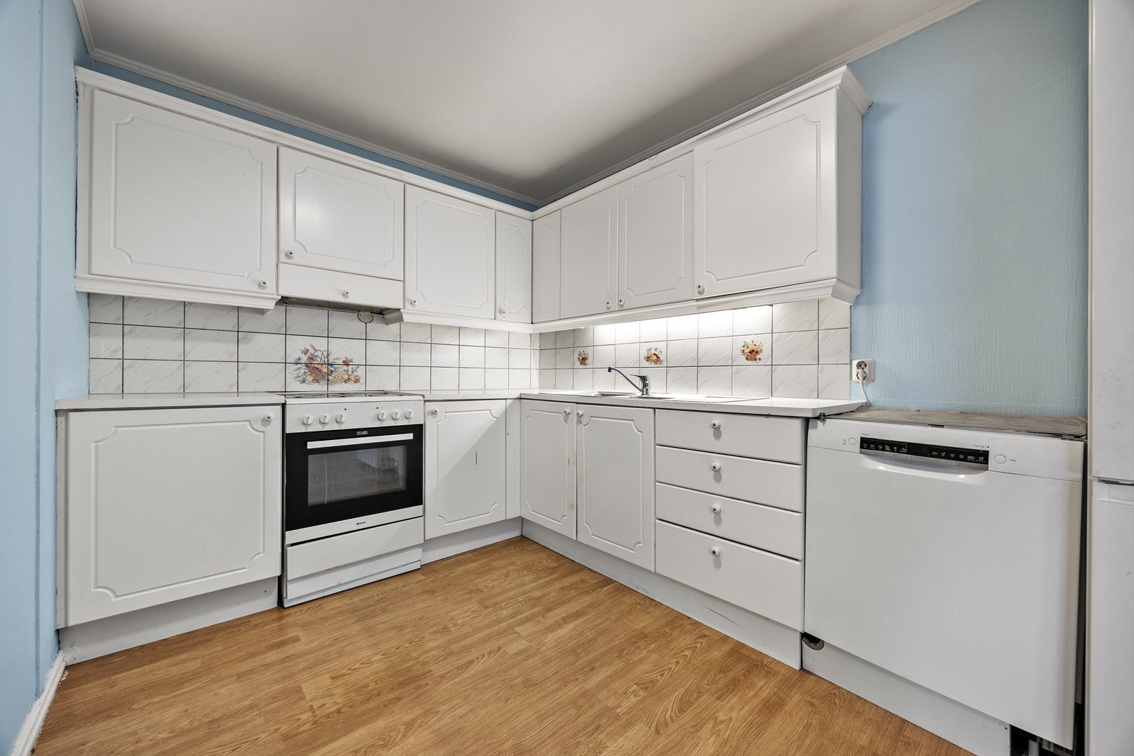 Kjøkkenet er praktisk innredet med hvit skapinnredning med profilerte fronter og laminat benkeplate. Galleribilde