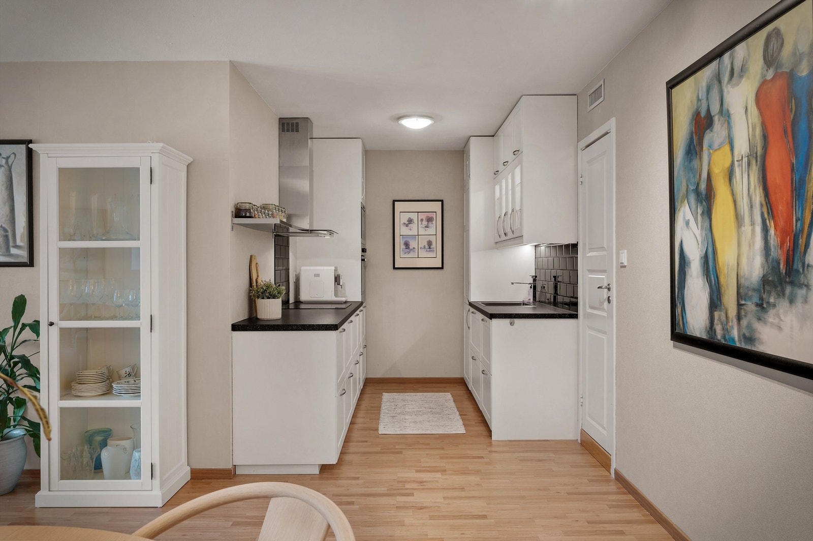 Innbydende og klassisk hvit kjøkkeninnrednig med sort benkeplate samt matchende veggfliser over. Galleribilde