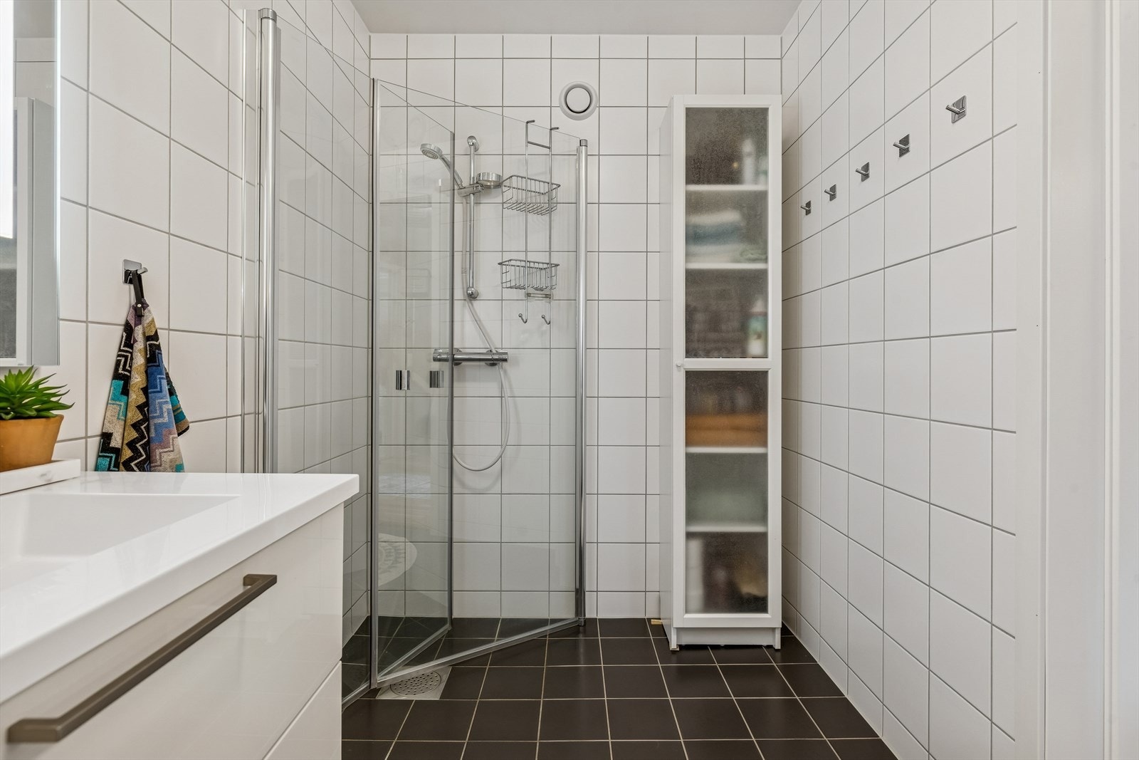 Badet i tredje etasje har dusjhjørne med innfellbare dører og flislagte overflater. Galleribilde