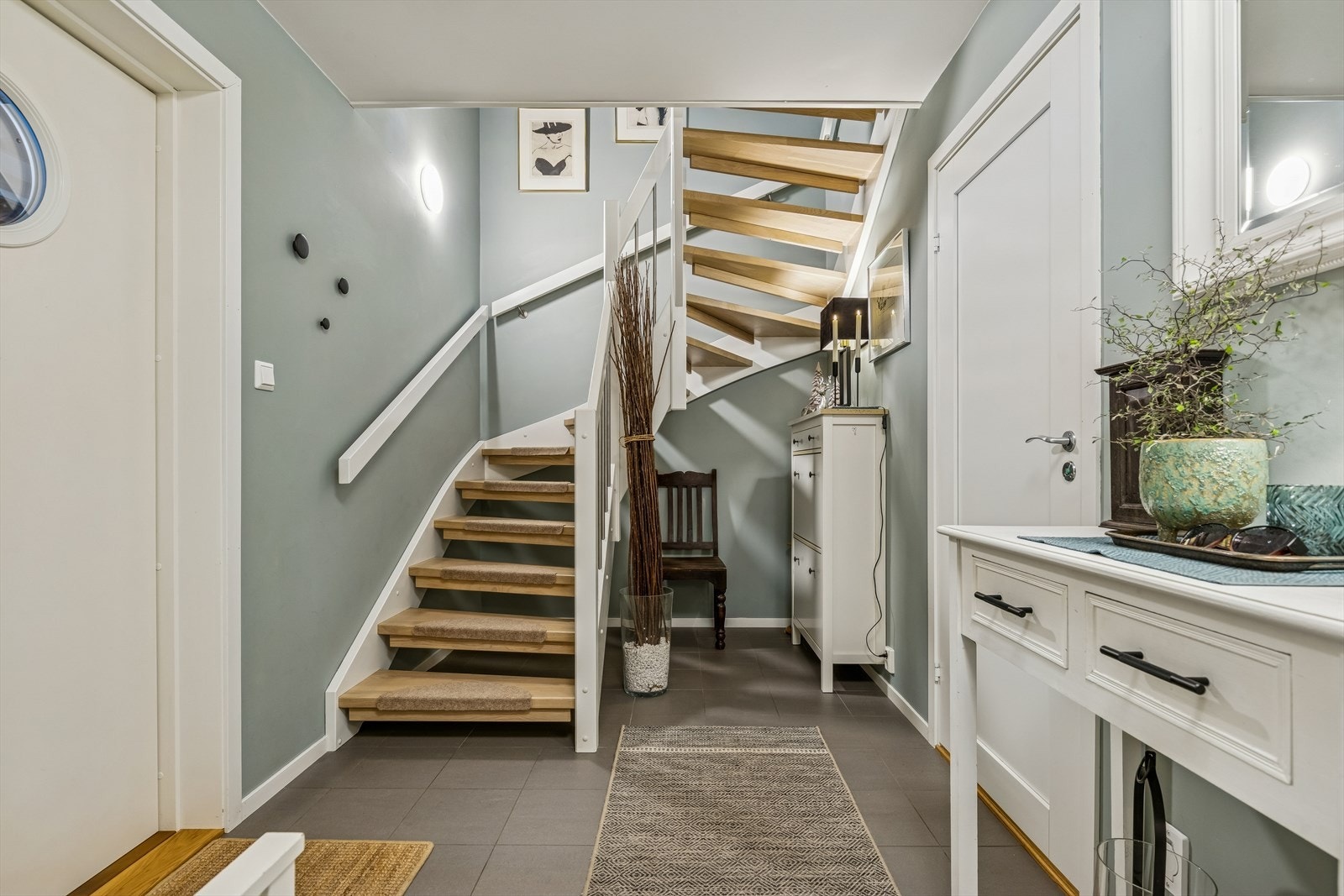 Entréen har flislagt gulv med gulvvarme og trapp som binder sammen boligens tre plan. Galleribilde