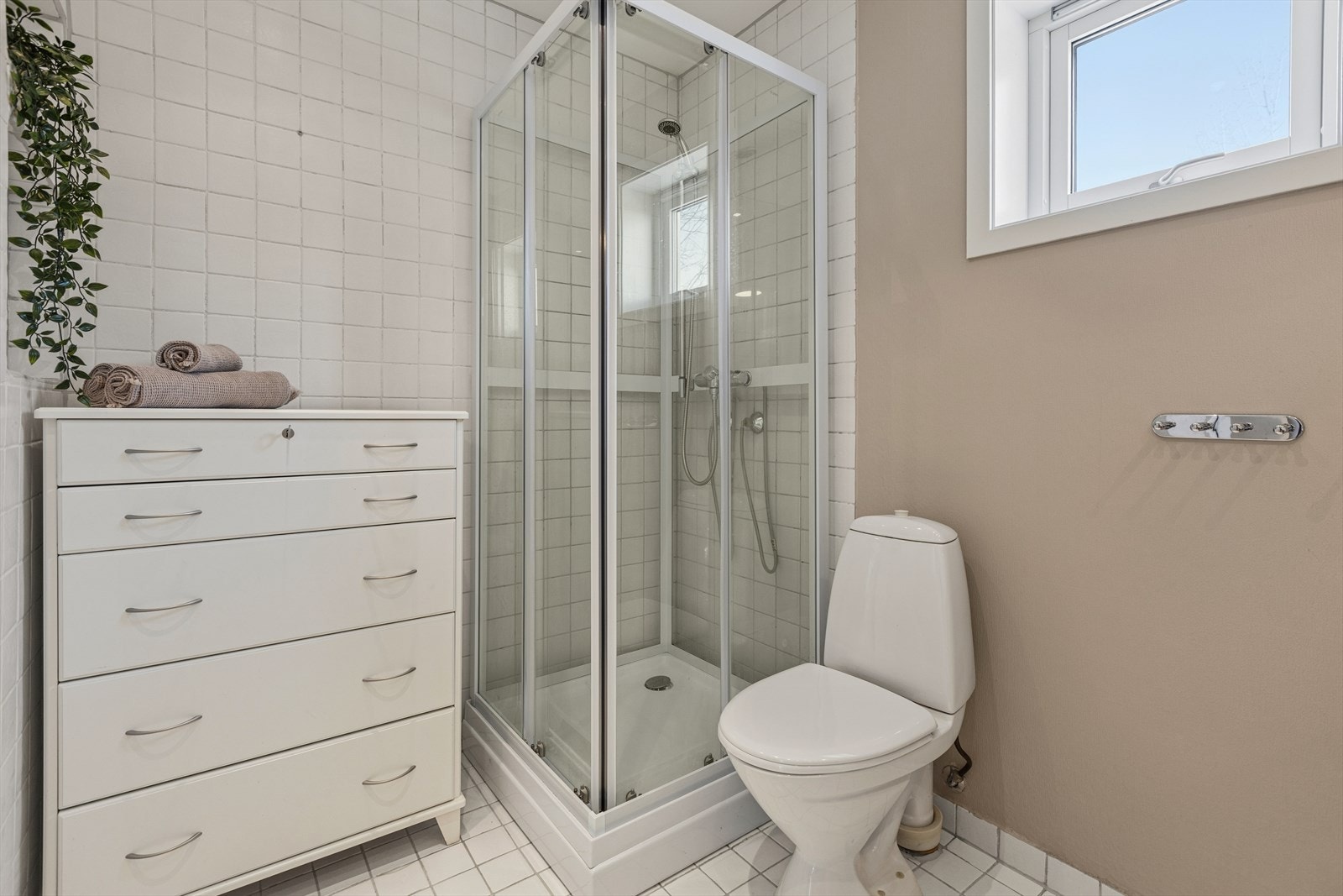 Badet er lyst og har flislagt gulv med varmekabler. Utstyrt med dusjkabinett og gulvstående toalett. Galleribilde