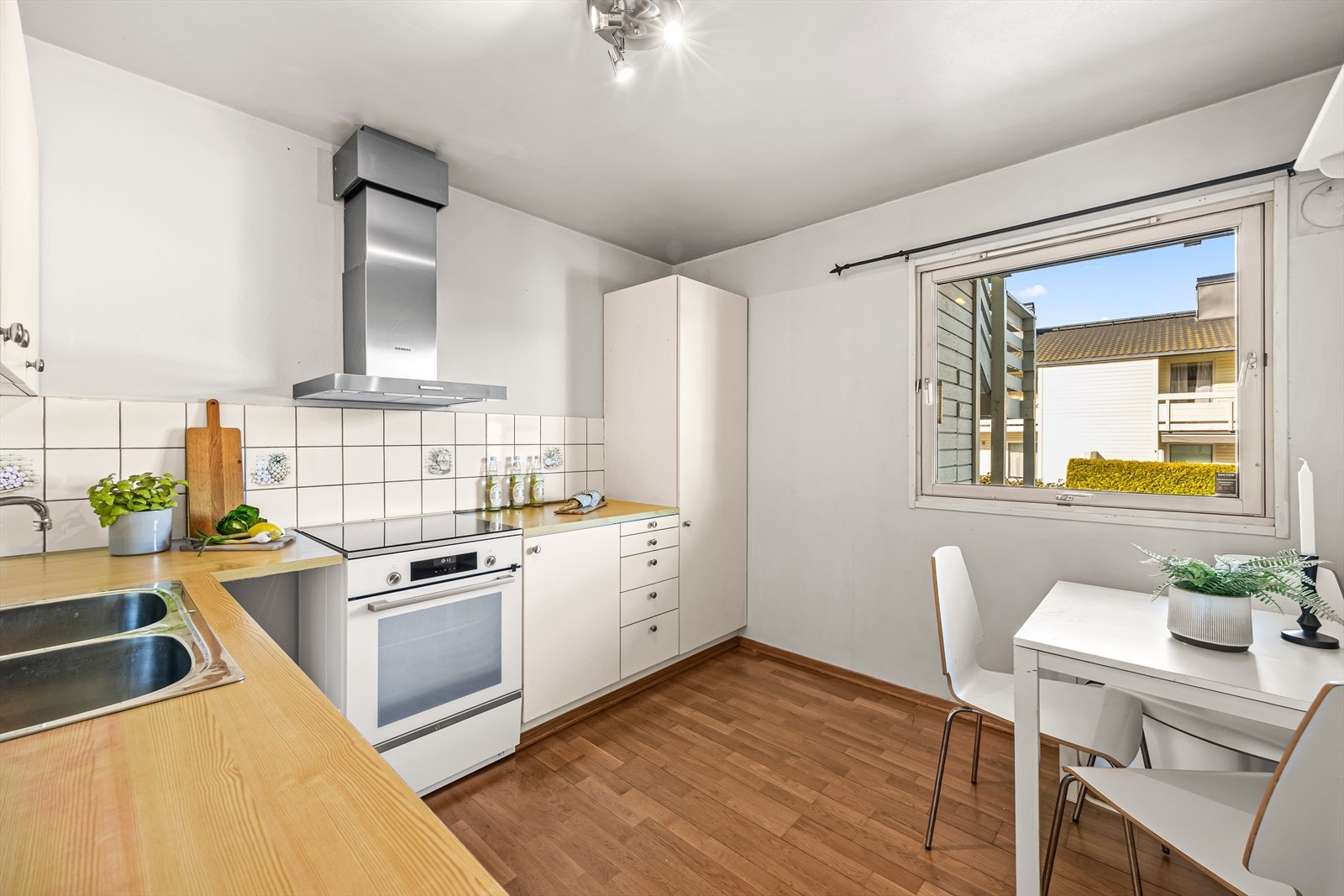 Eldre kjøkkeninnredning med lys innredning bestående av glatte fronter og laminert benkeplate med kjøkkenkran og nedfelt kum. Galleribilde