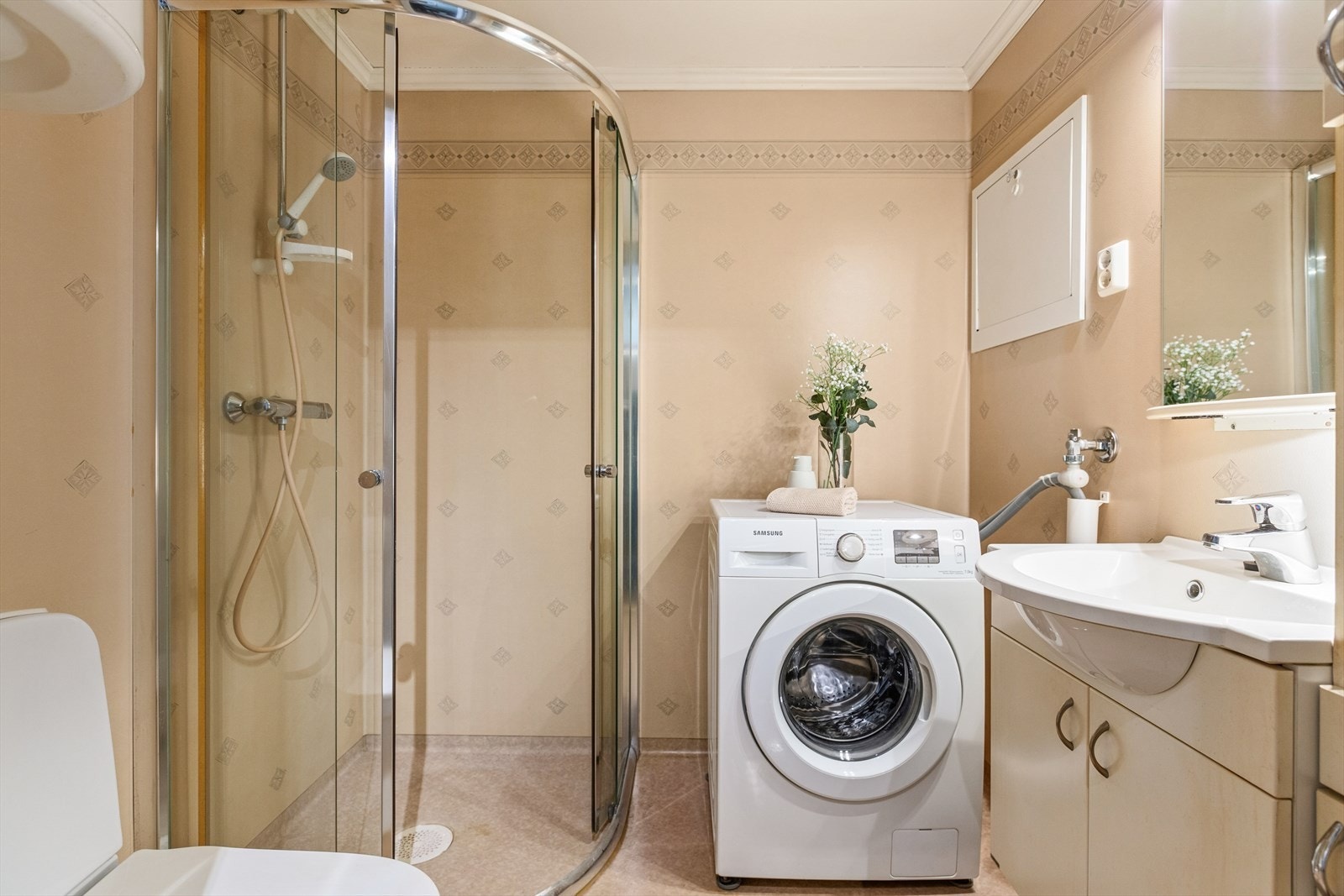 Badet måler 3,5 m² og er utstyrt med blant annet gulvvarme, opplegg for vaskemaskin, dusjhjørne og servant med tilhørende oppbevaring. Galleribilde