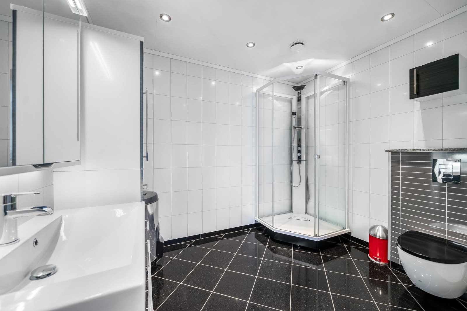 Badet inneholder dusjkabinett, servant med skapinnredning og veggopphengt toalett. Galleribilde