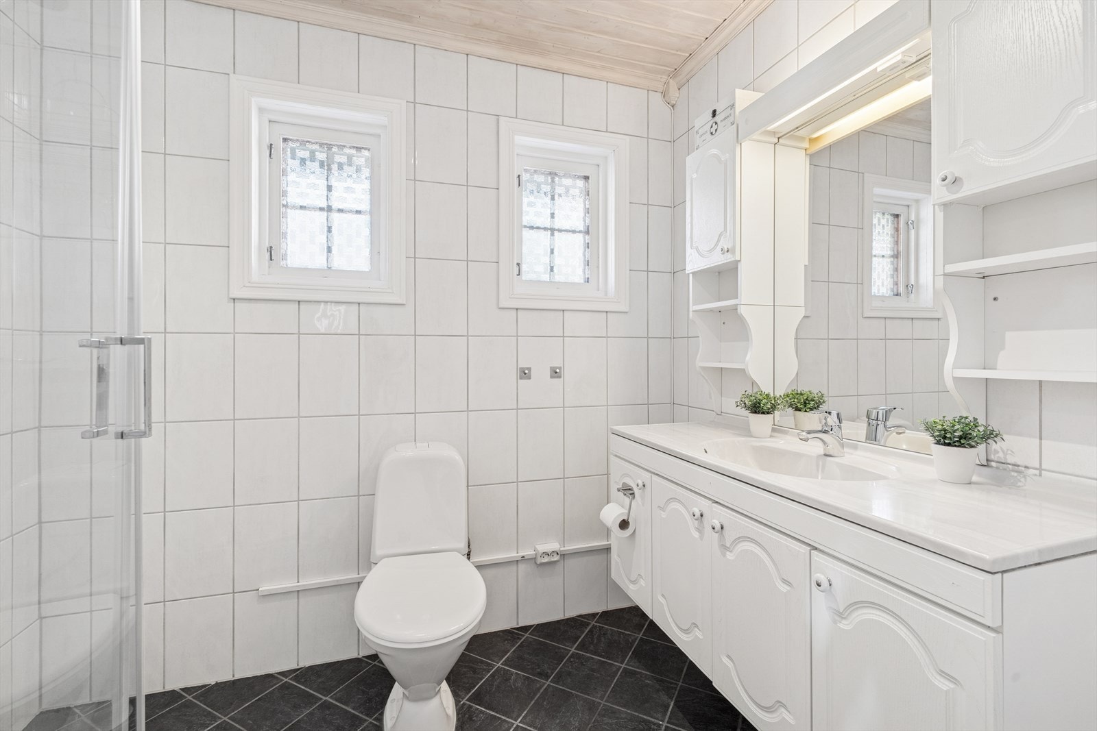 Badet i 1. etasje med dusj, gulv-montert toalett, og servant i innredning Galleribilde