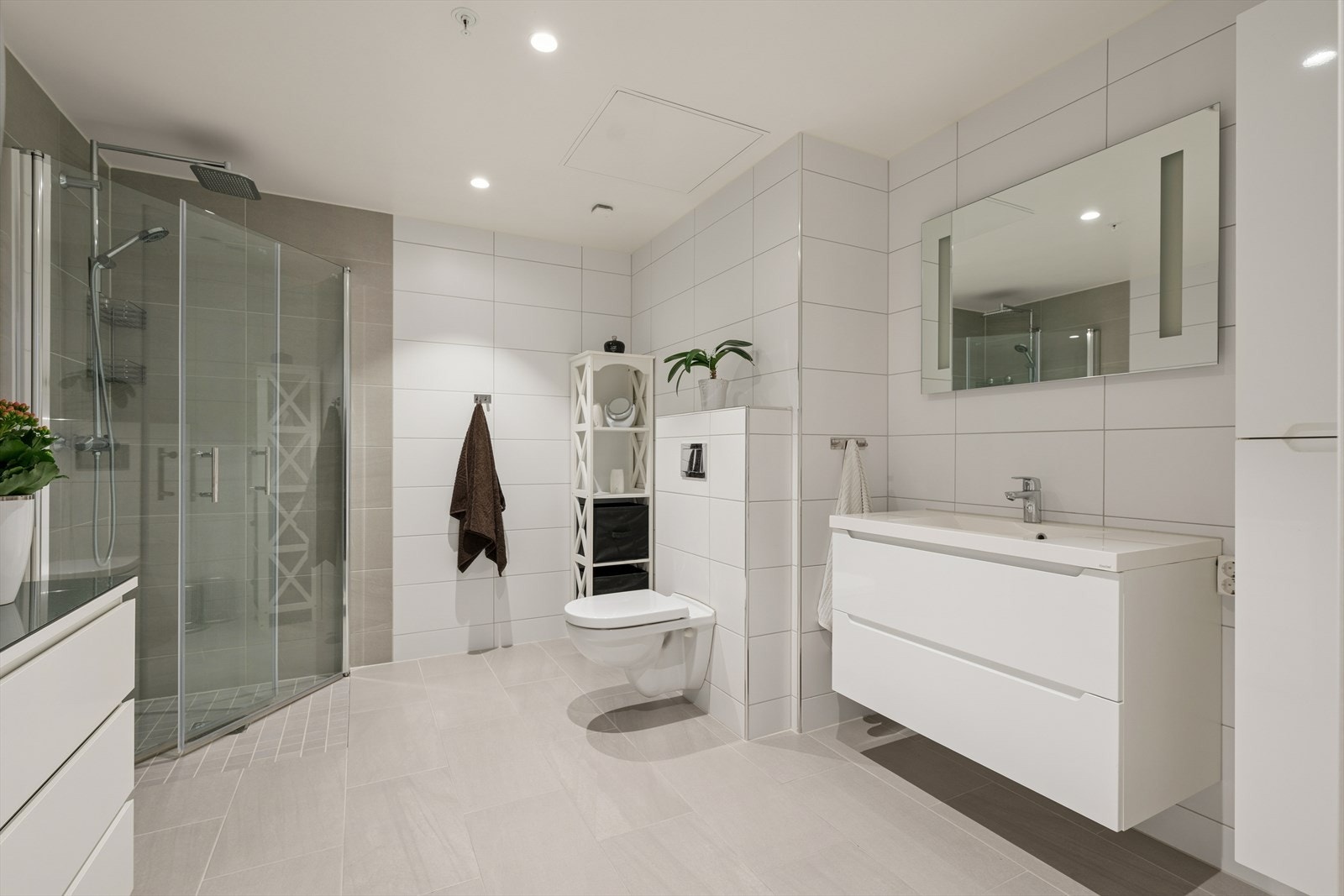 Svært delikat bad med flislagte overflater og gulvvarme. Dusjhjørne med regndusj og hånndusj, samt vegghengt toalett. Galleribilde