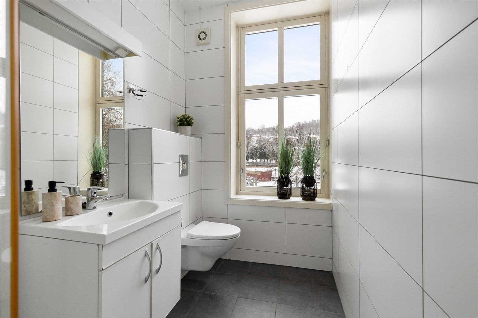 Lyst og pent baderom med flislagte gulv og vegger. Galleribilde