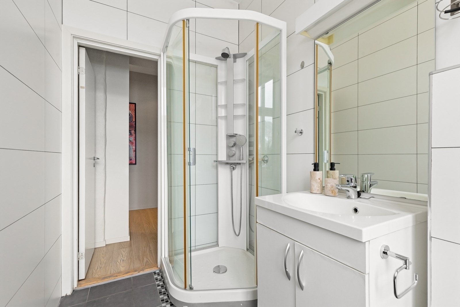 Innredningen består av en servantseksjon med skuffer som gir oppbevaringsplass, dusjkabinett, vegghengt toalett og speil med integrert belysning. Galleribilde