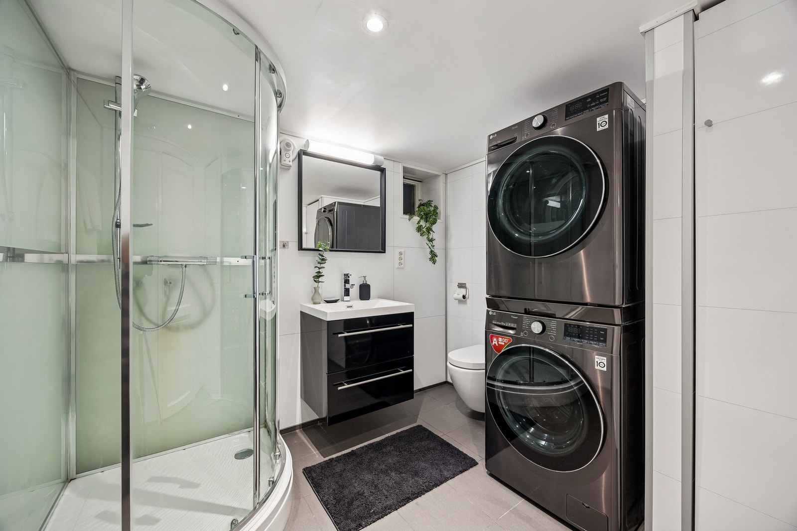 Badrommet i kjeller måler 5 kvm og ble oppgradert i 2021. Badet er innredet med vegghengt servantinnredning, speil med overlys, dusjkabinett, vegghengt toalett og opplegg for vaskemaskin. Galleribilde