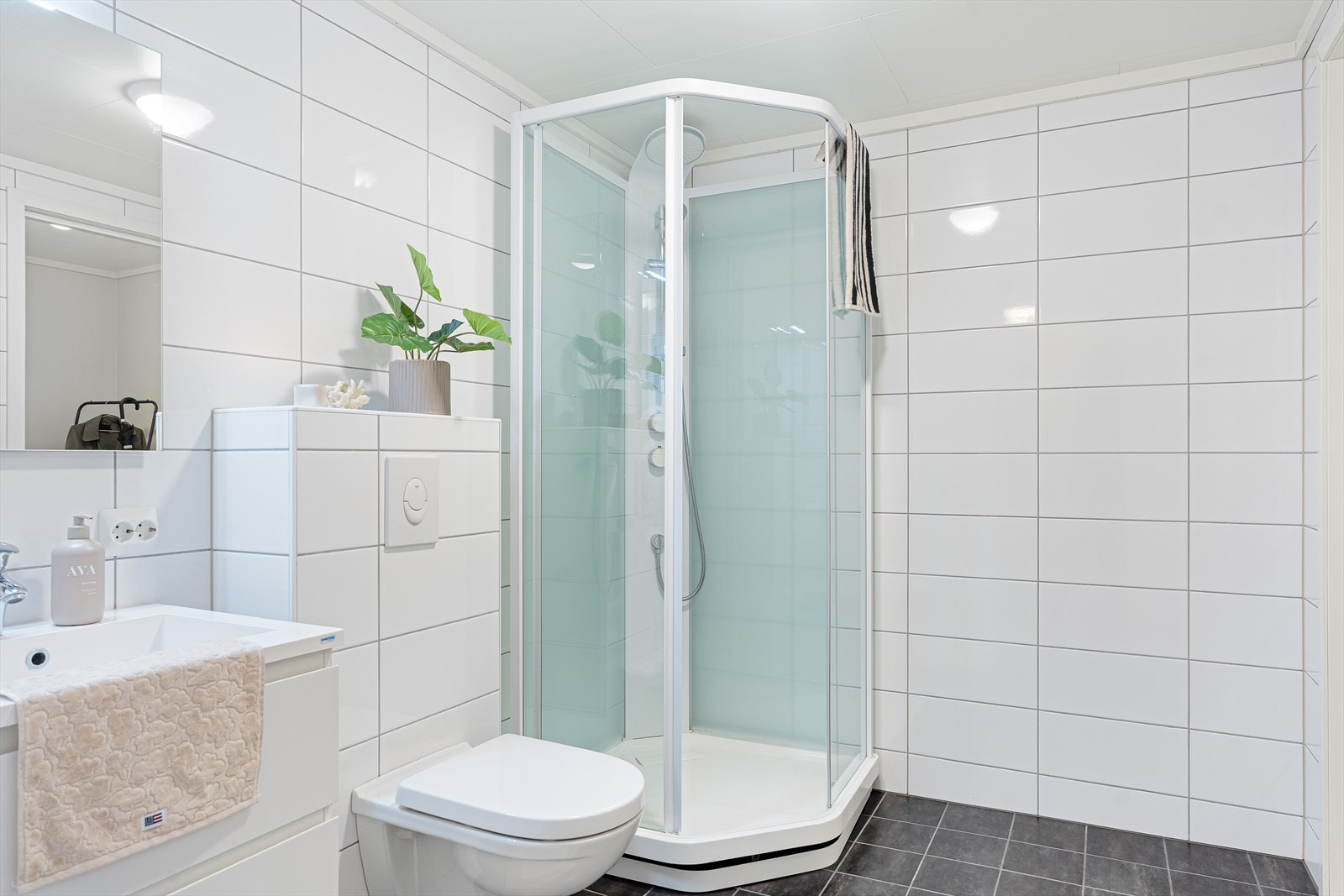 Pent bad, innredet med baderomsmøbel med heldekkende servant, veggmontert toalett og dusjkabinett. Galleribilde