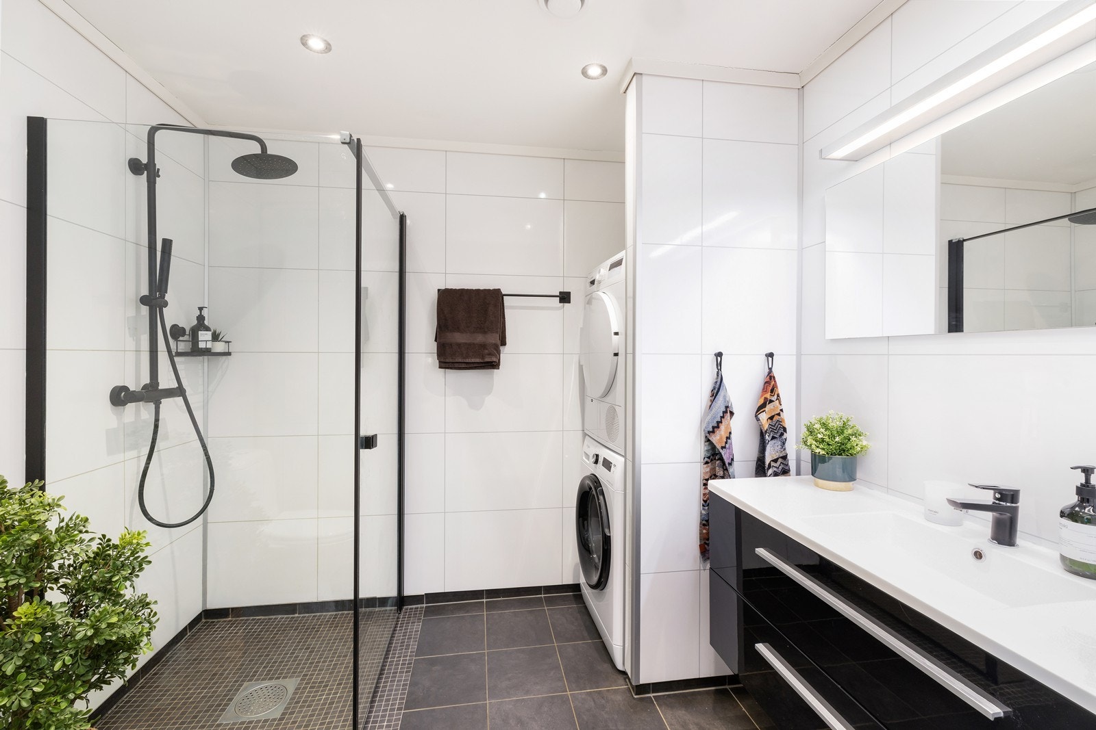 Leiligheten har et pent og moderne bad. Legg merke til nisje for vaskemaskin og tørketrommel. Galleribilde