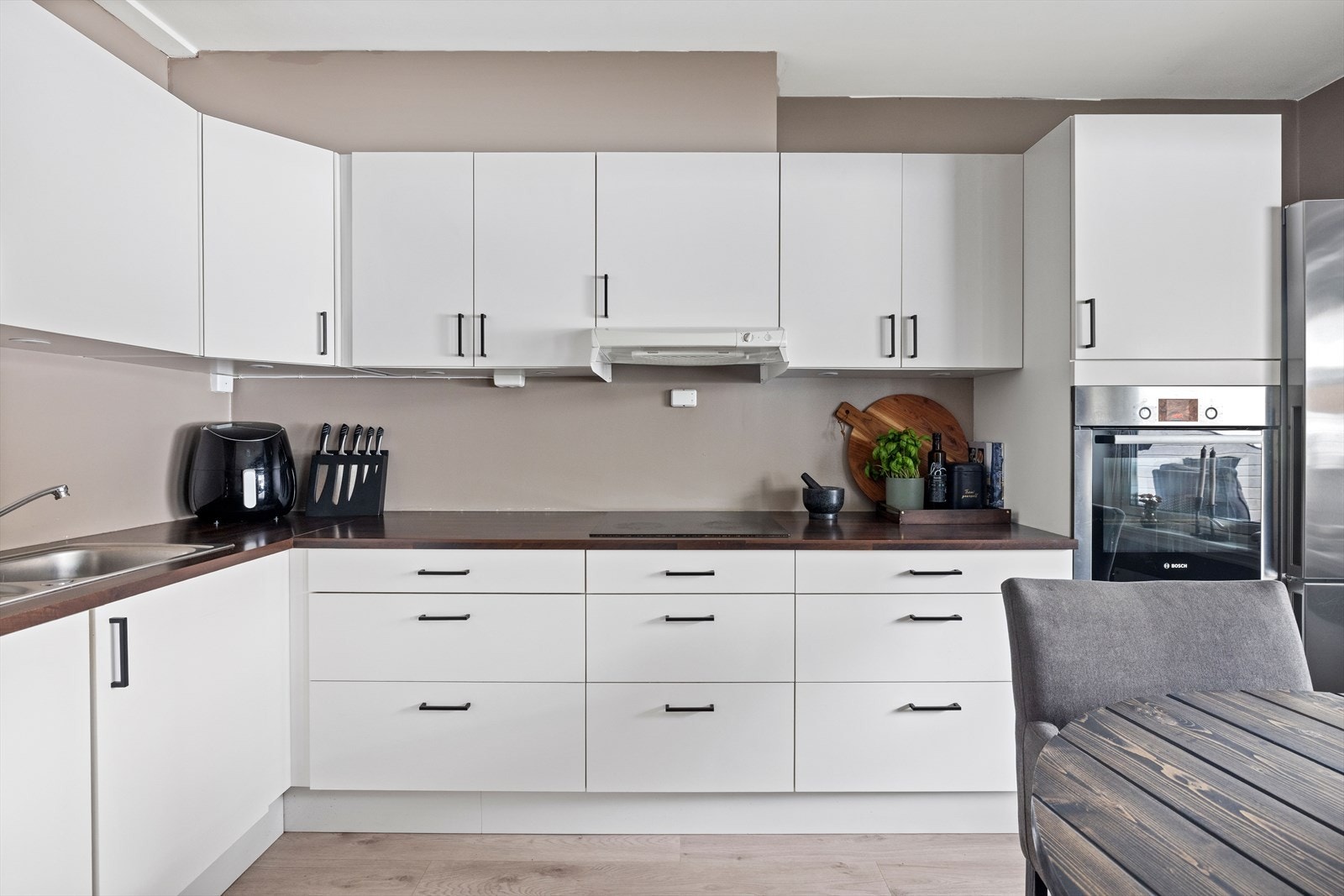 Innredningen har slette fronter, laminat benkeplate og integrerte hvitevarer som stekeovn, platetopp og oppvaskmaskin Galleribilde