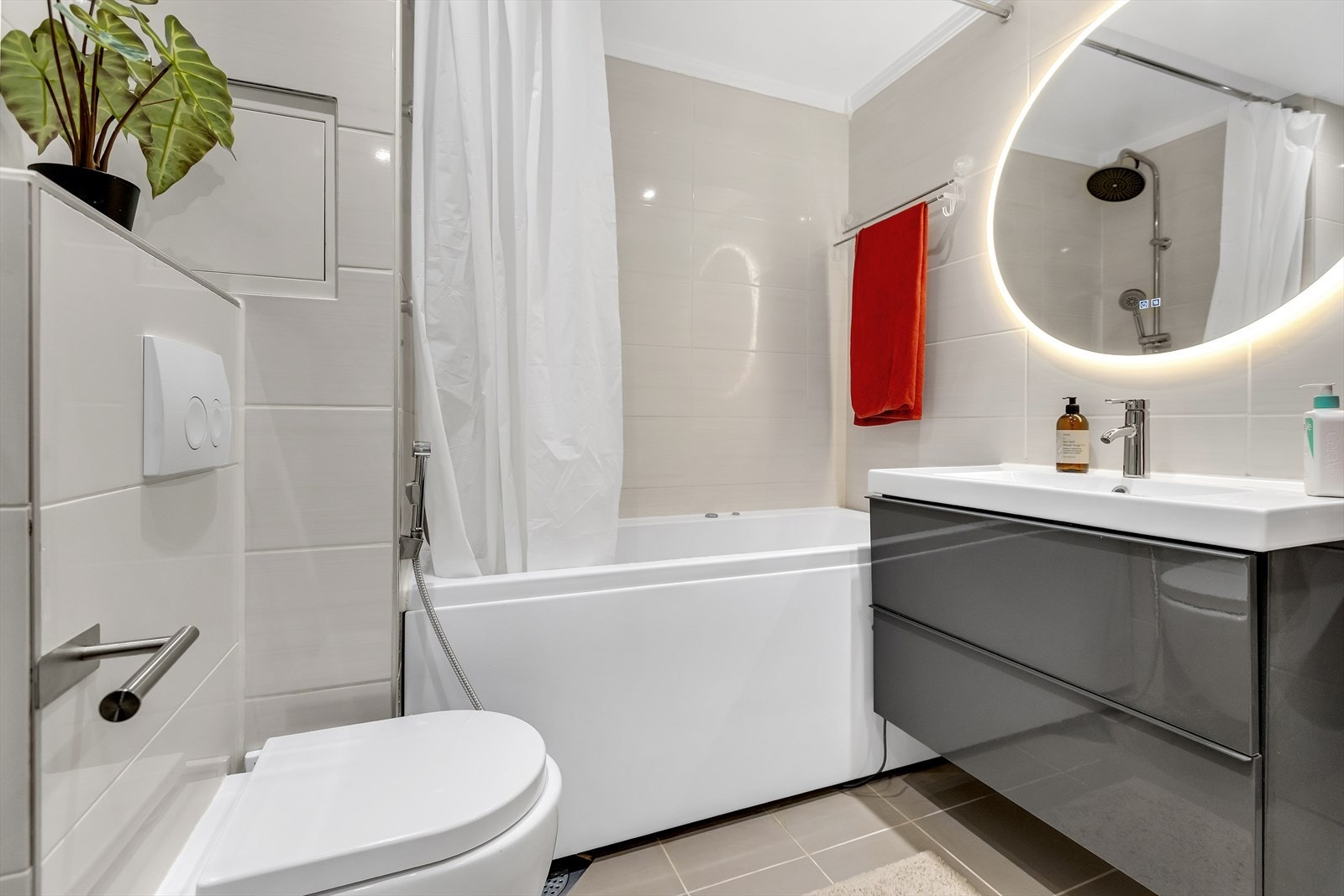 Delikat bad med moderne innredning, speil med belysning og badekar/dusjløsning. Galleribilde