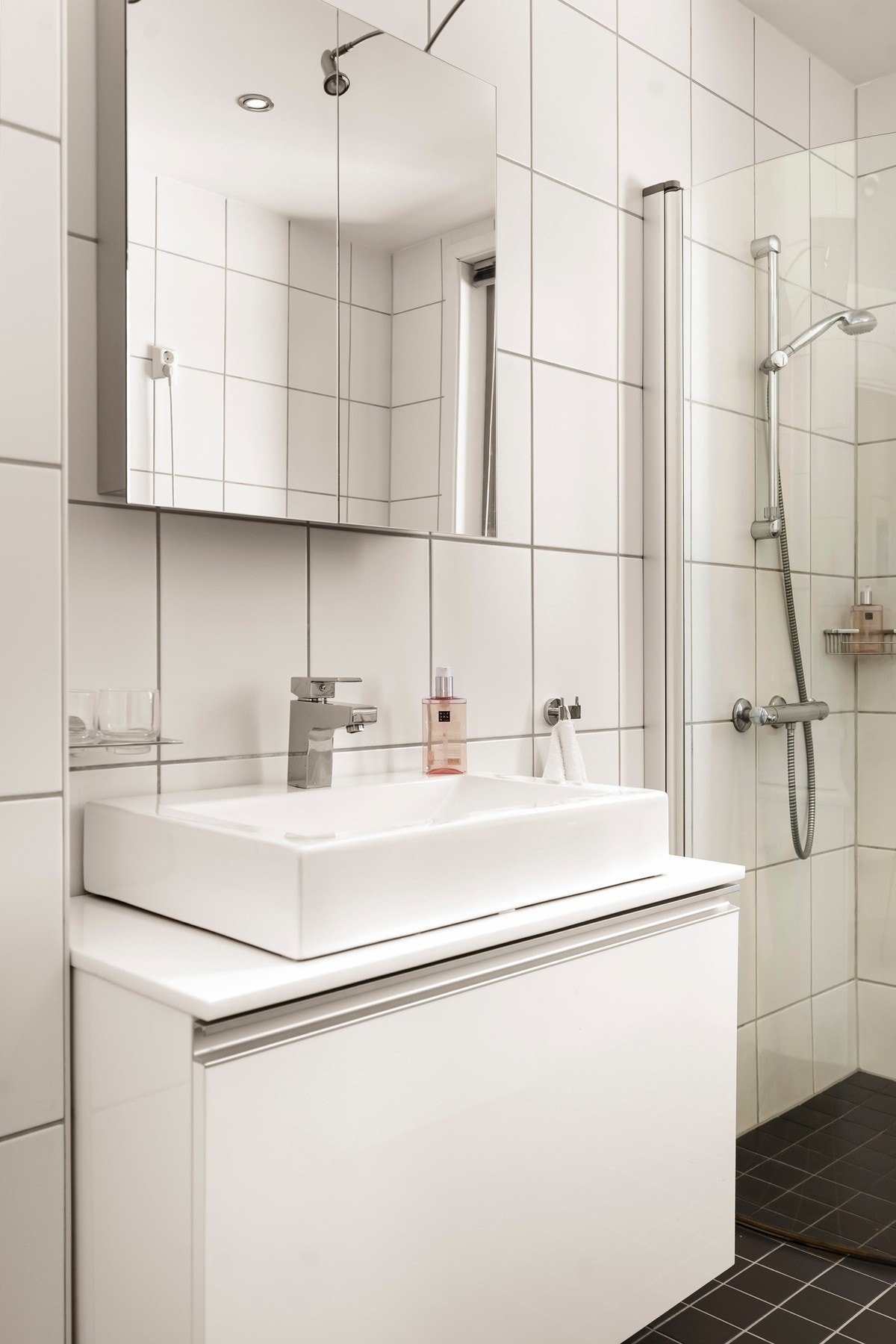 Badet har vegghengt servantinnredning med skuff og ovenpåliggende servant, samt speil med belysning på vegg over servant. Galleribilde