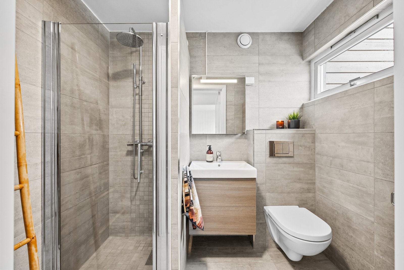 Innredning og garnityr på bad fremstår med: veggmontert WC, dusjplass i nisje og servant med ettgreps blandebatteri i innredning. Galleribilde