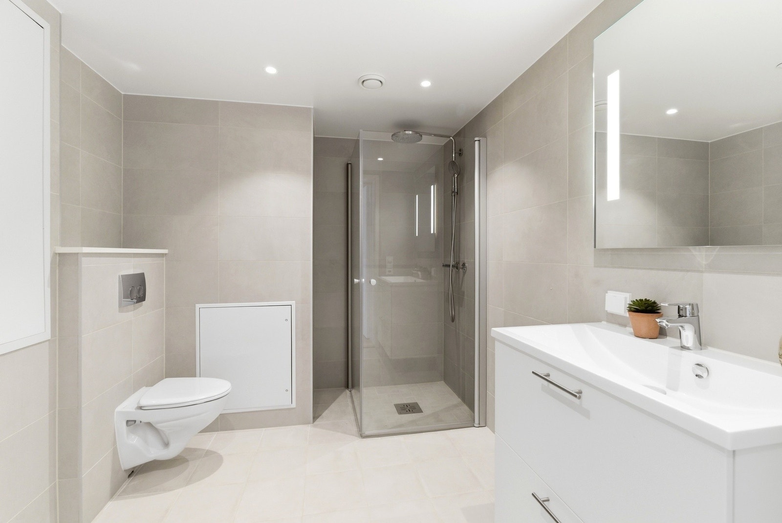 Stilrent og pent flislagt bad med varme i gulv og downlights i himling. Dusjhjørne med innfellbare vegger og regnfall/hånddusj. Galleribilde