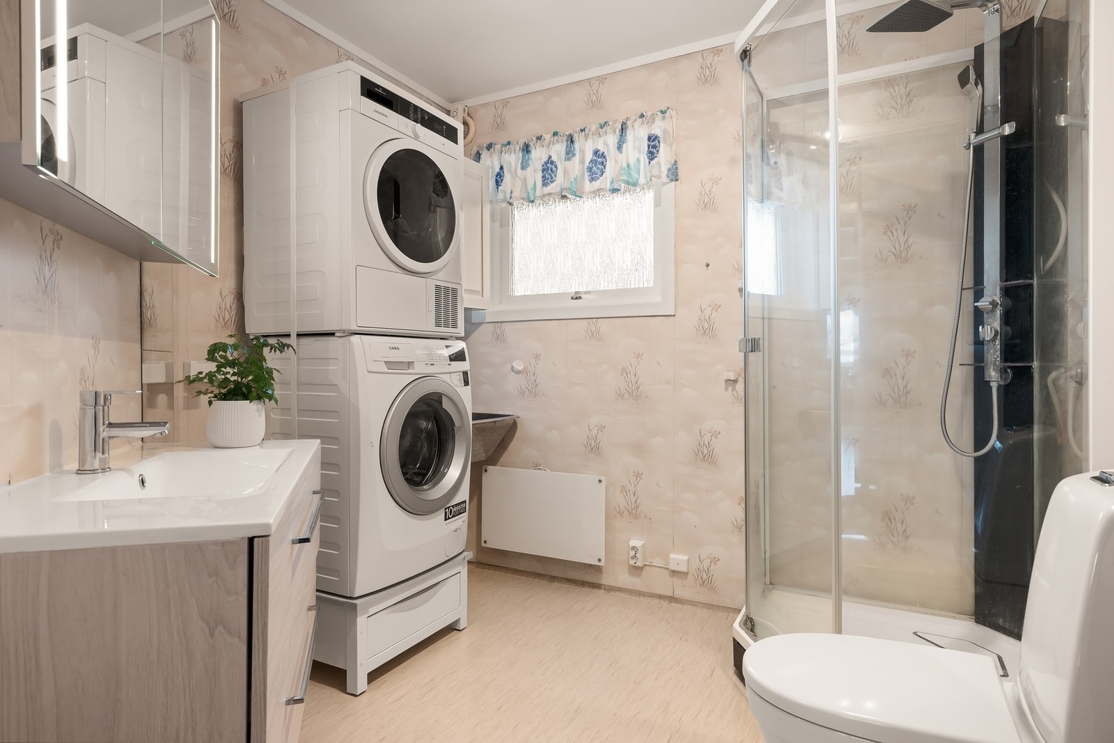 Praktisk baderom med toalett, dusjkabinett, opplegg for vaskemaskin/tørketrommel, servantinnredning og speilskap. Galleribilde