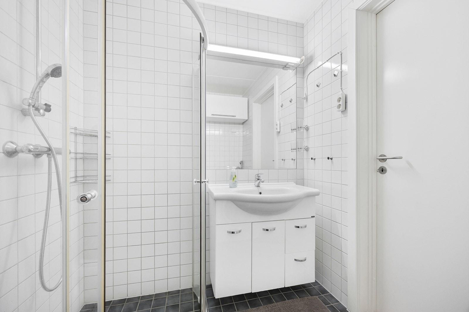 Badet er innredet med servant i baderomsinnredning, dusjhjørne, vegghengt toalett og opplegg for vaskemaksin. Galleribilde