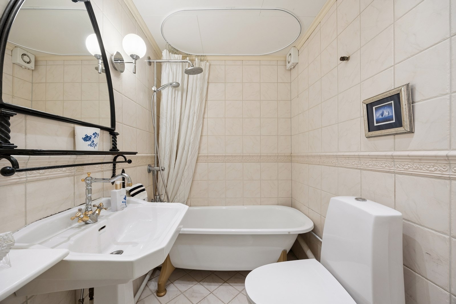 Flislagt bad med servant, toalett og badekar med dusj. Galleribilde