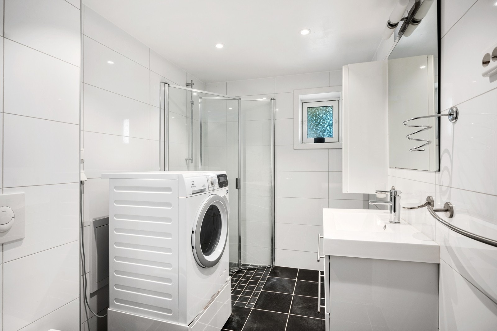 Flislagt baderom i underetasjen med vegghengt servantskap, dusj på gulv med innfellbare glassdører og vegghengt toalett Galleribilde