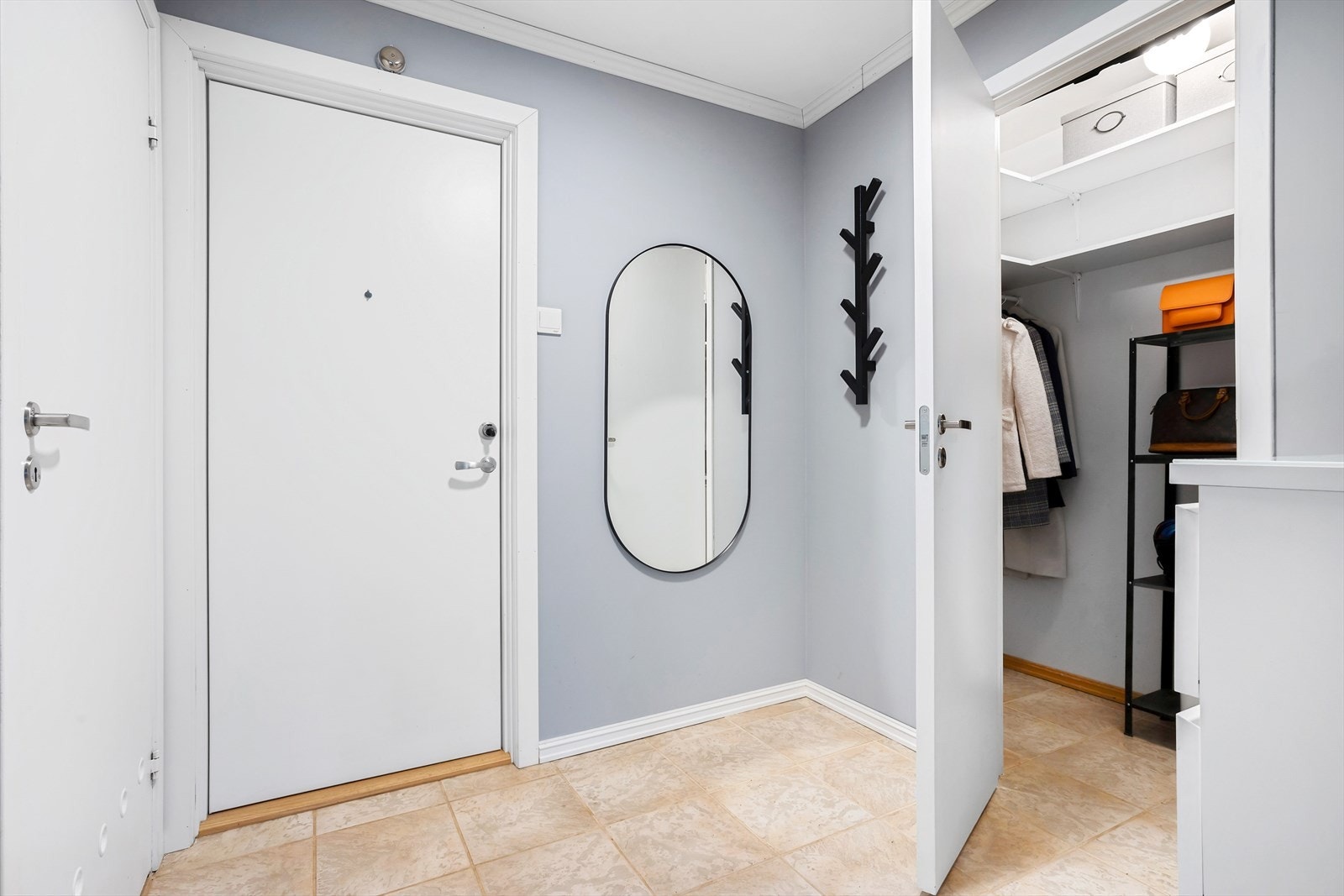 Romslig entré med flislagt gulv, malte veggflater og plass for oppbevaringsmøblement Galleribilde