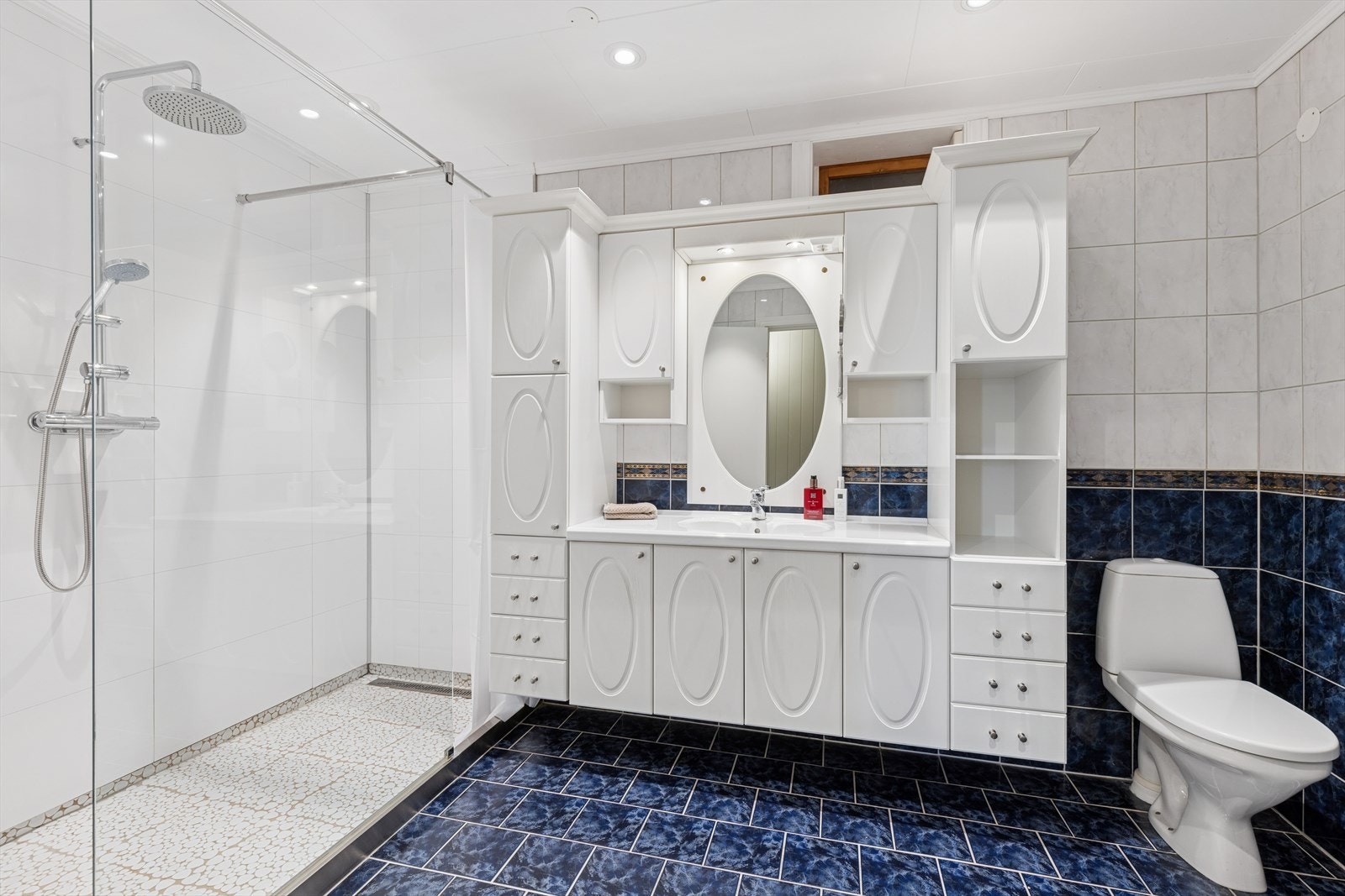 Stort og romslig baderom med lekker dusjsone, praktisk baderomsinnredning og WC Galleribilde