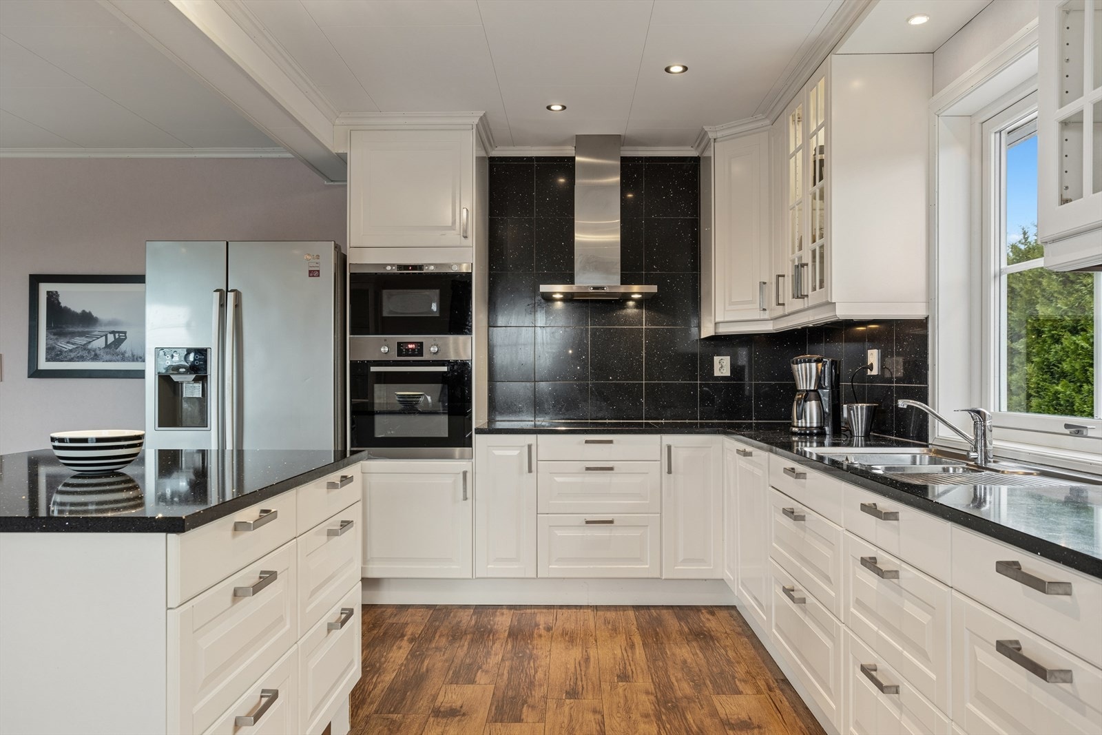 Moderne og romslig kjøkken med stilrene fronter og steinbenkeplate Galleribilde