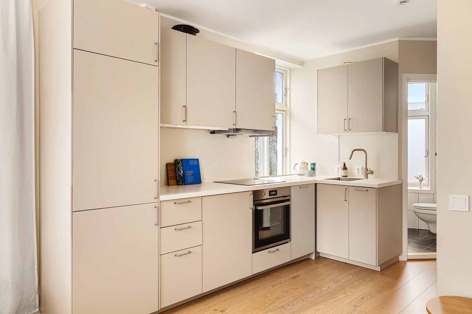 Kjøkkenet står i stil med resten av boligen og har innredning med glatte fronter. Her finner du benkeflate av laminat, kjøl/fryseskap, oppvaskmaskin, platetopp, stekeovn, vannstoppsystem, komfyrvaktog vaskemaskin. Galleribilde