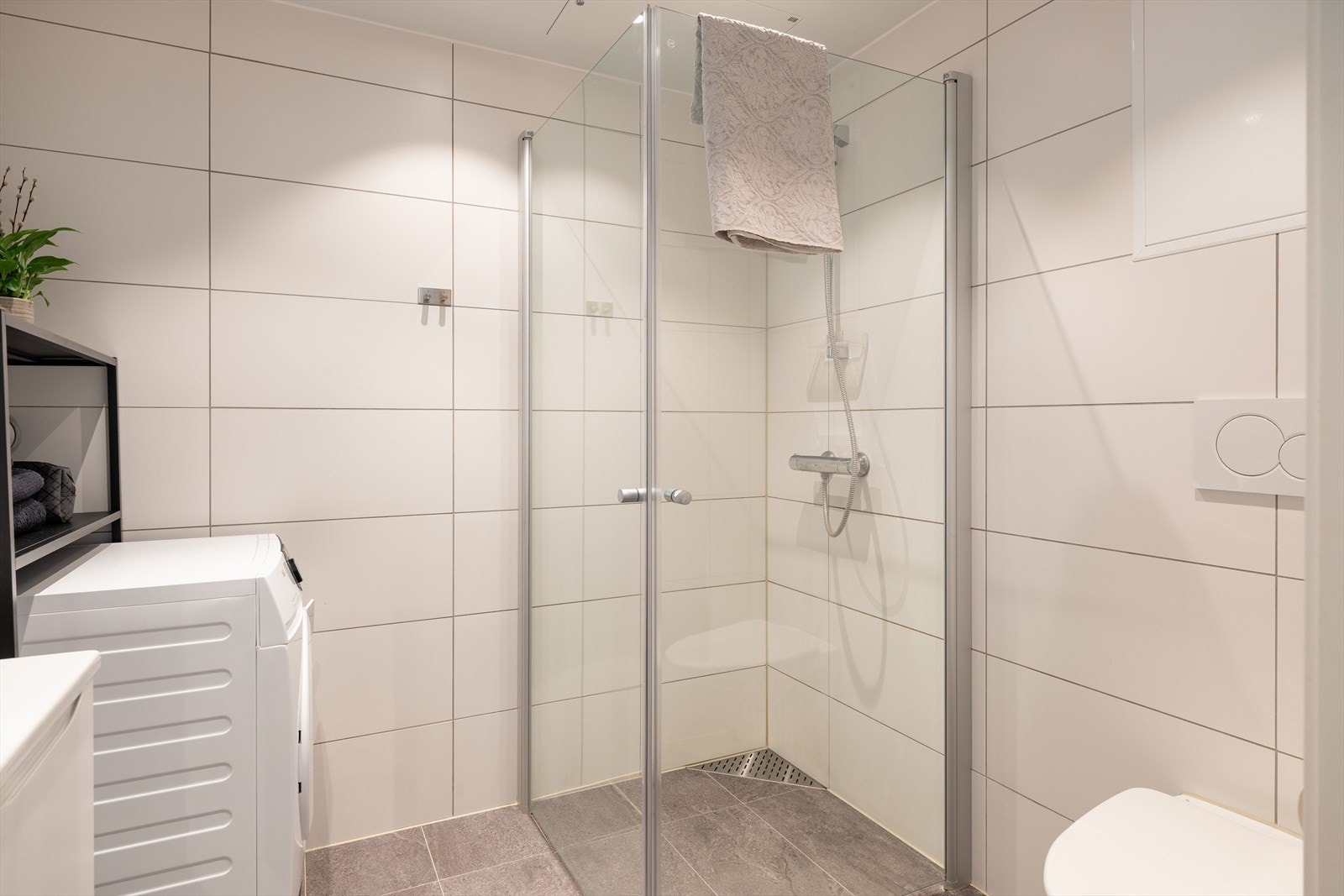 Baderommet er utstyrt med innfellbare dusjdører, baderomsinnredning, vegghengt klosett og opplegg for vaskemaskin. Galleribilde