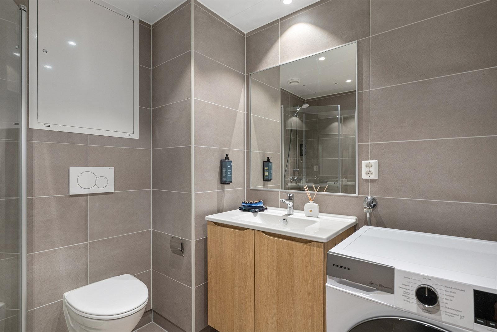 Vegghengt toalett og tidsriktige overflater gir et stilrent helhetsinntrykk. Galleribilde