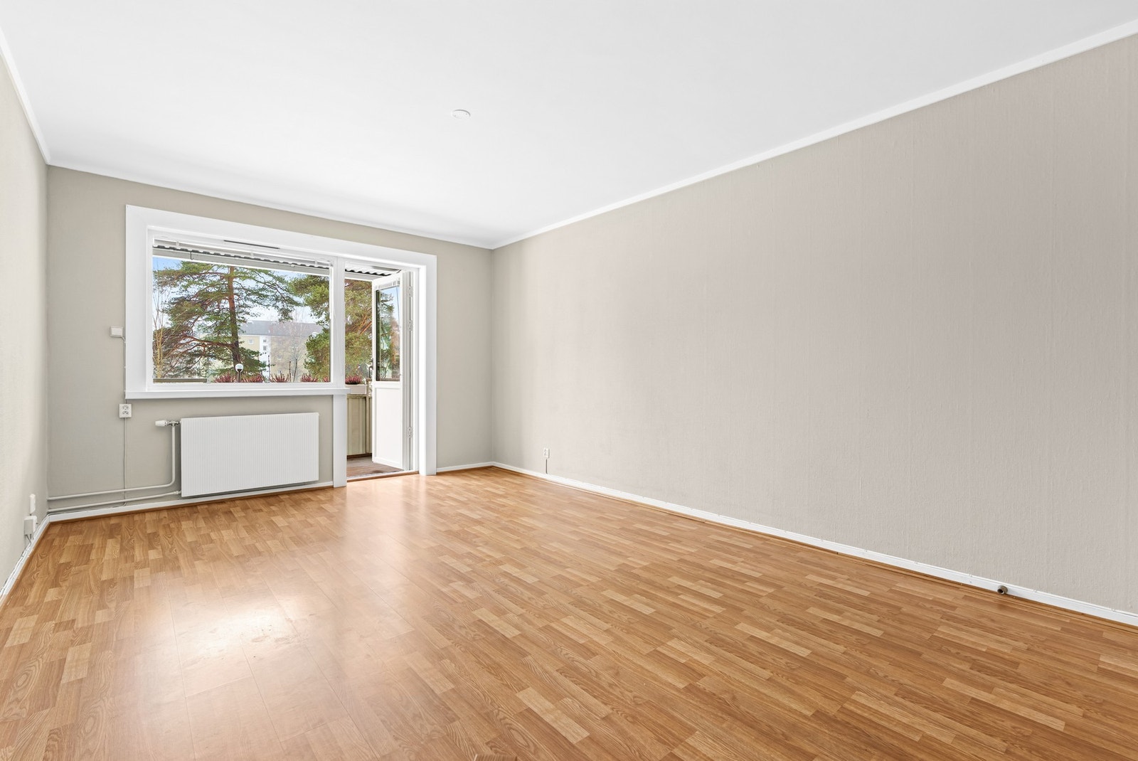 Veggene i stuen er malt opp i duse farger, og rommet varmes opp med felles fjernvarme via radiator. Galleribilde