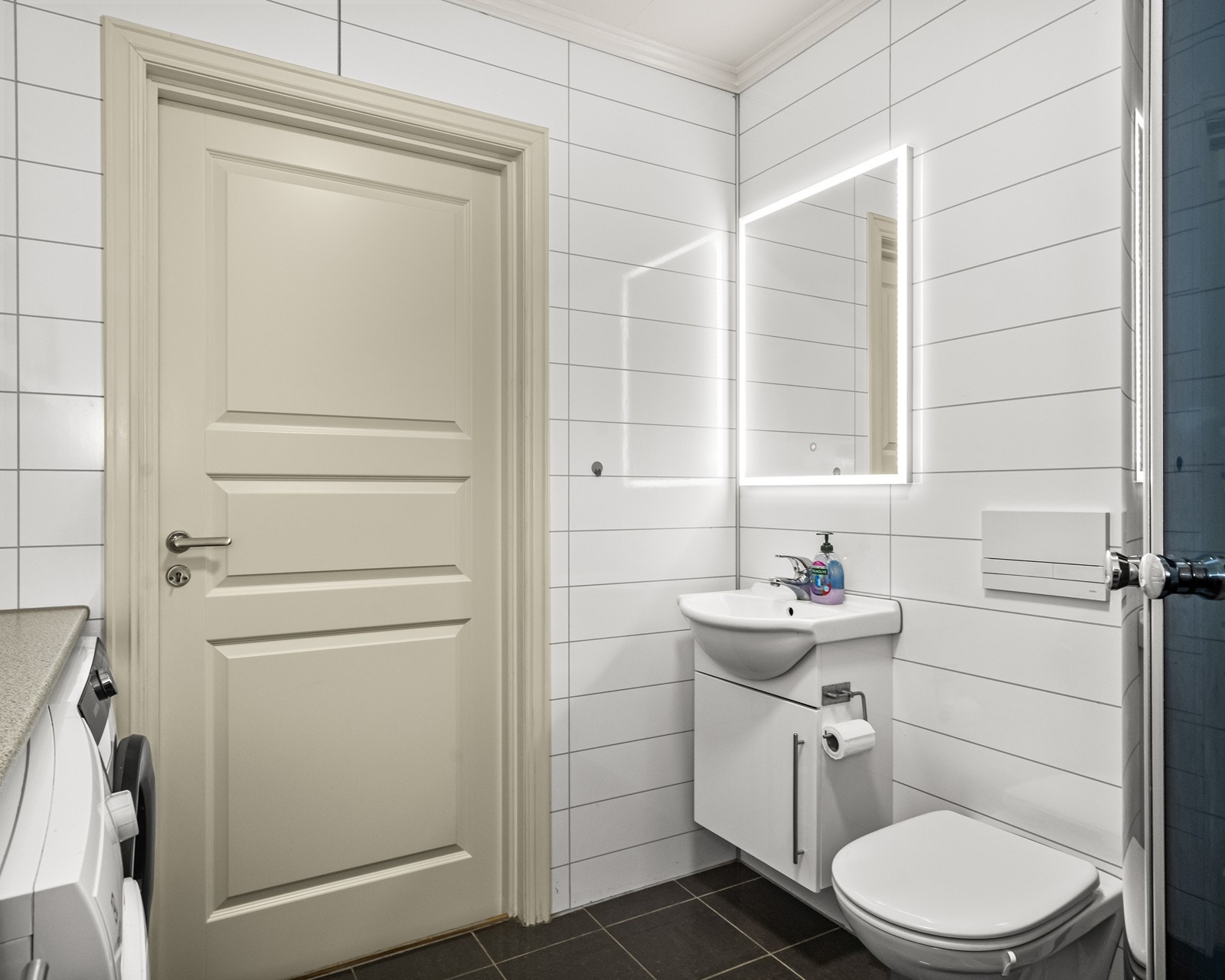 Vegghengt toalett og moderne baderomsinnredning med høyglans fronter skaper et stilrent uttrykk. Galleribilde