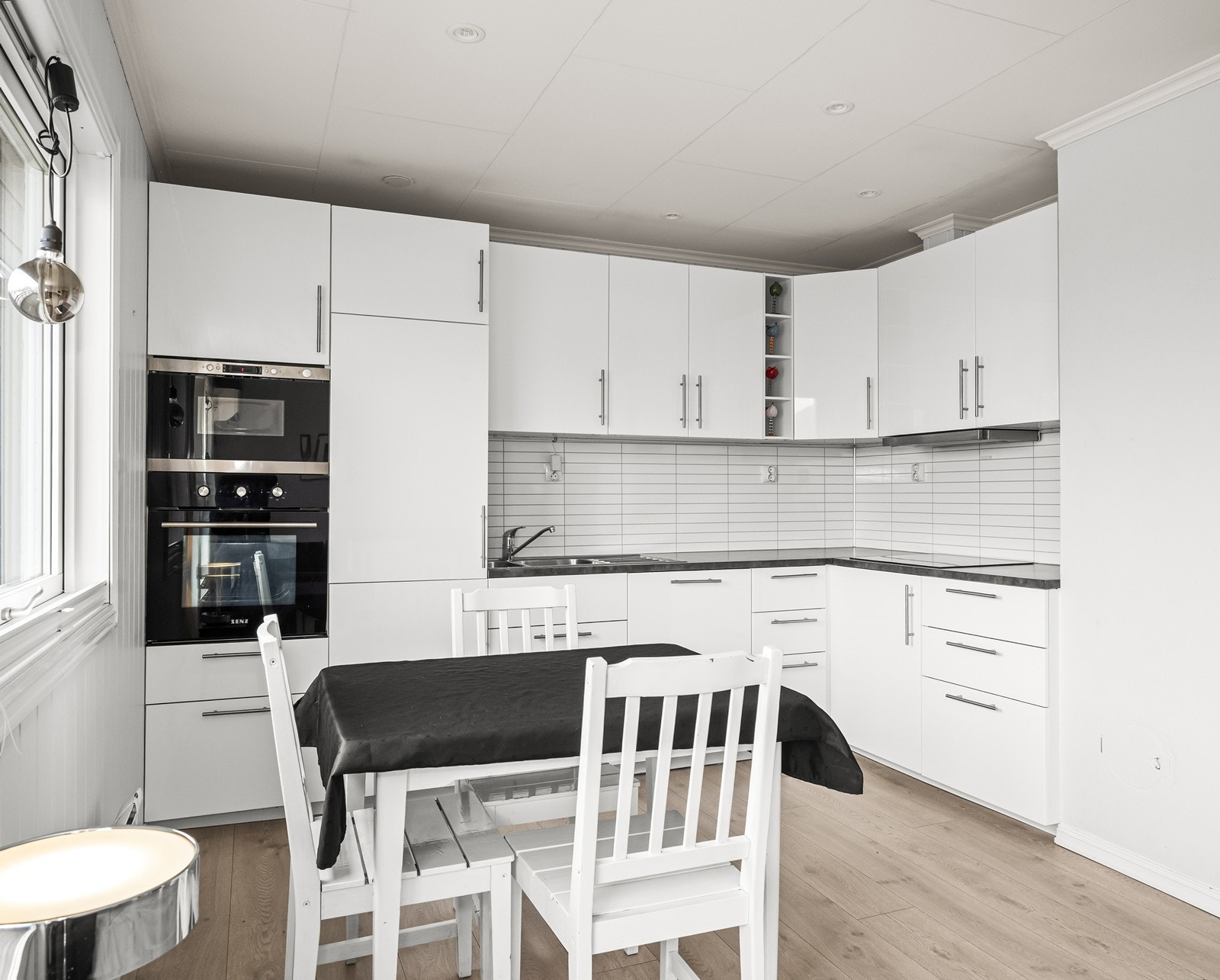 Kjøkkeninnredning i L-form med hvite profilerte fronter gir effektiv oppbevaring. Galleribilde