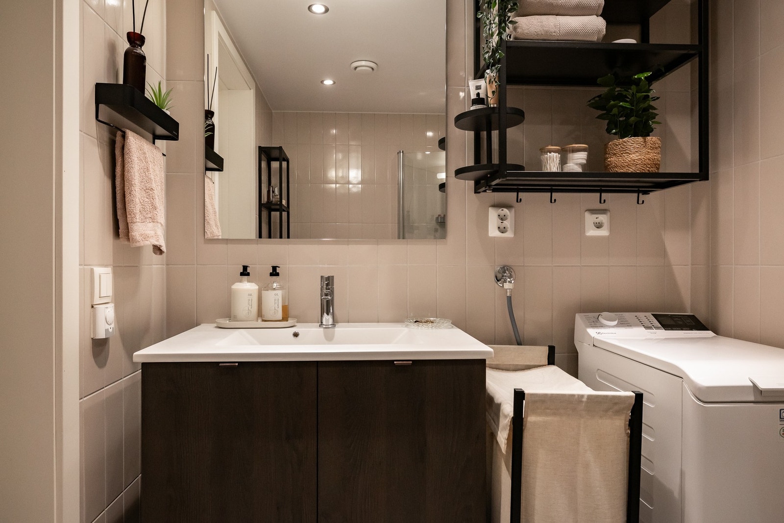 Innredningen består av servant med skap i mørk trestruktur, veggmontert speil, vegghengt toalett og dushjørne med svingbare dører i glass. Galleribilde