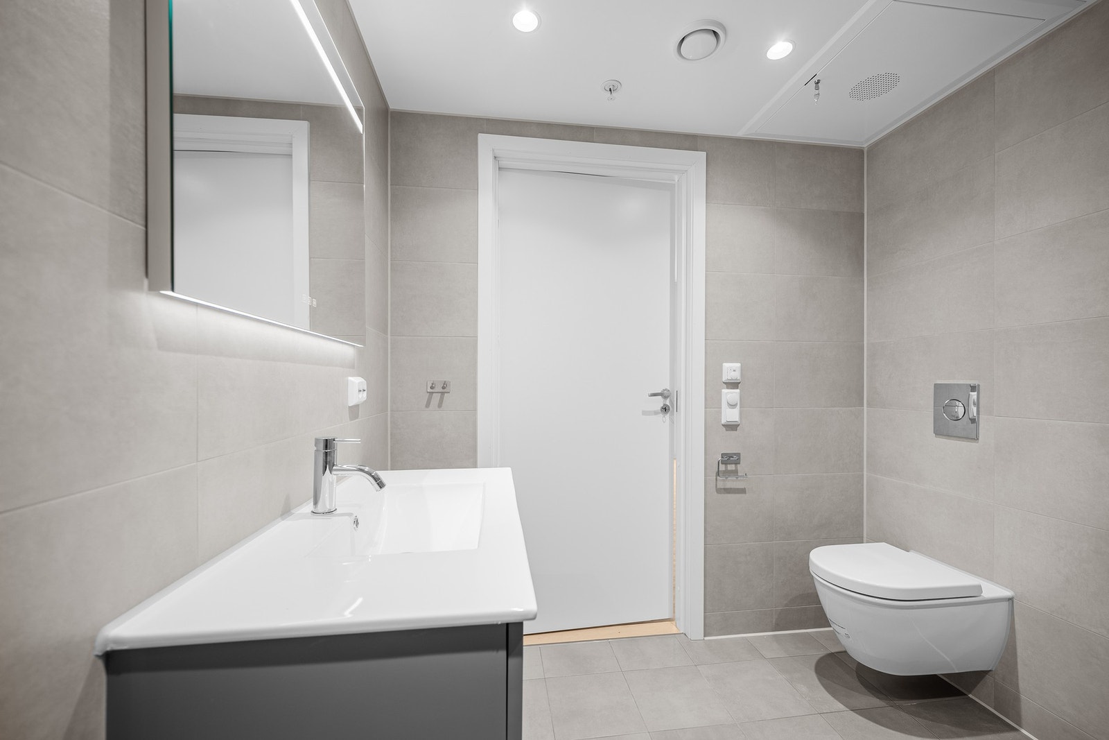 Baderomsinnredning med to skuffer for oppbevaring, med speil over og vegghengt toalett. Galleribilde