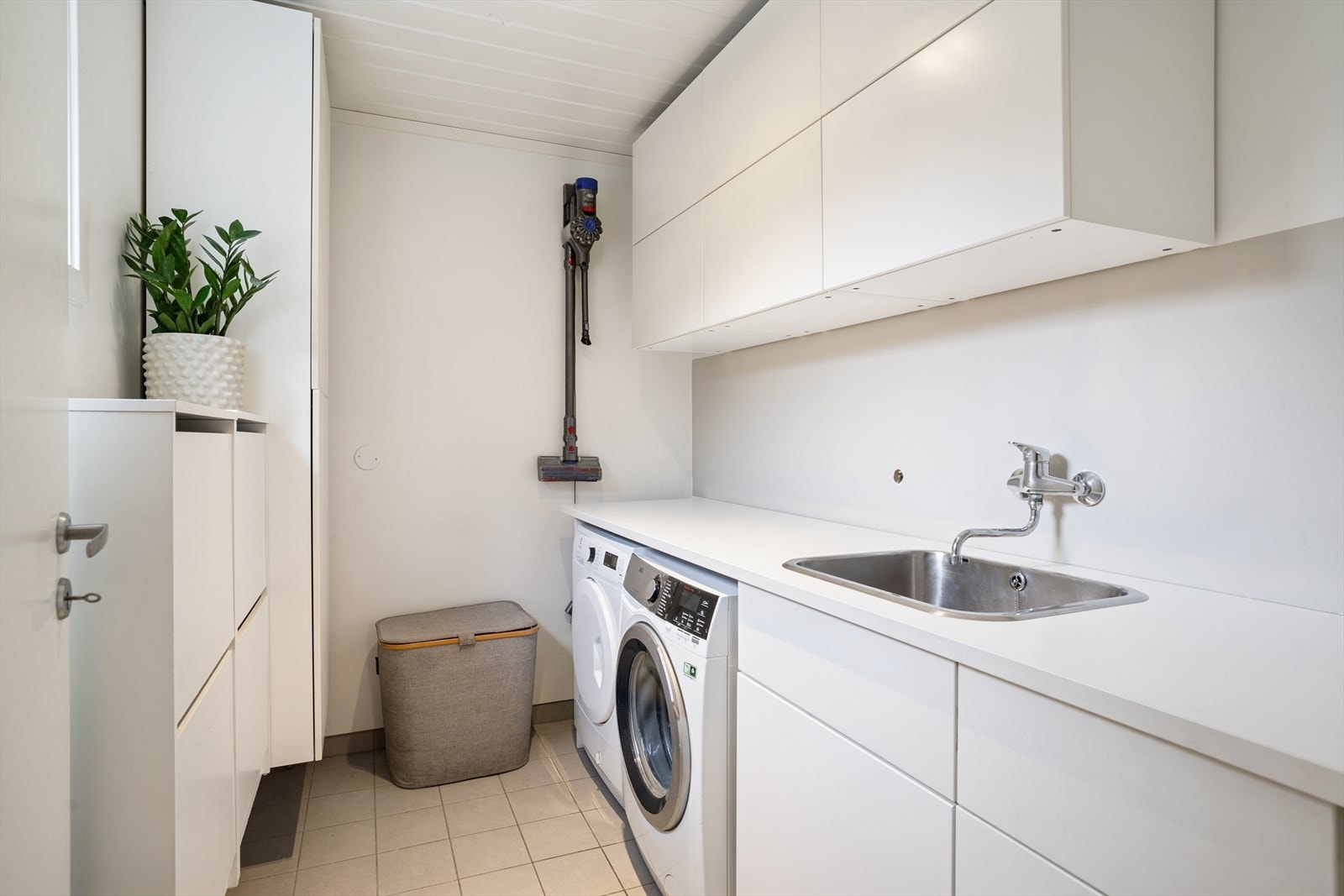 Vaskerommet i 1. etasje har malte vegger kombinert med sokkelfliser og flislagt gulv, og er utstyrt med hvit innredning. Galleribilde