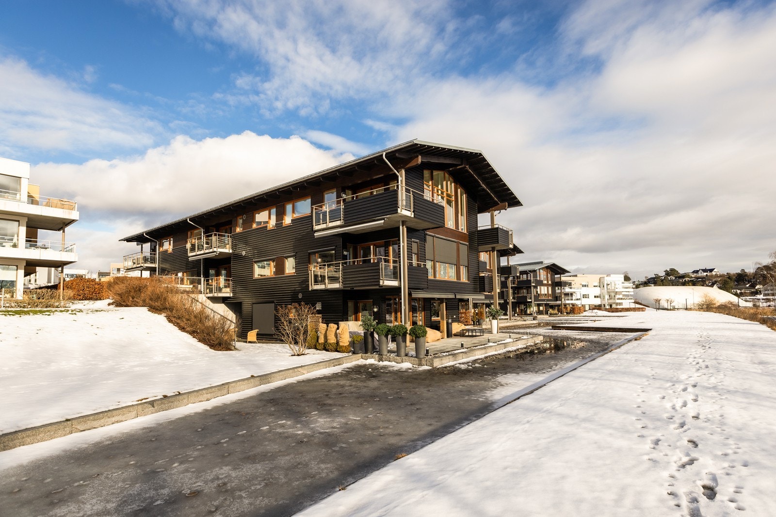 Store frie fellesarealer med gress, beplantning og vannspeil i front av bygget. Galleribilde