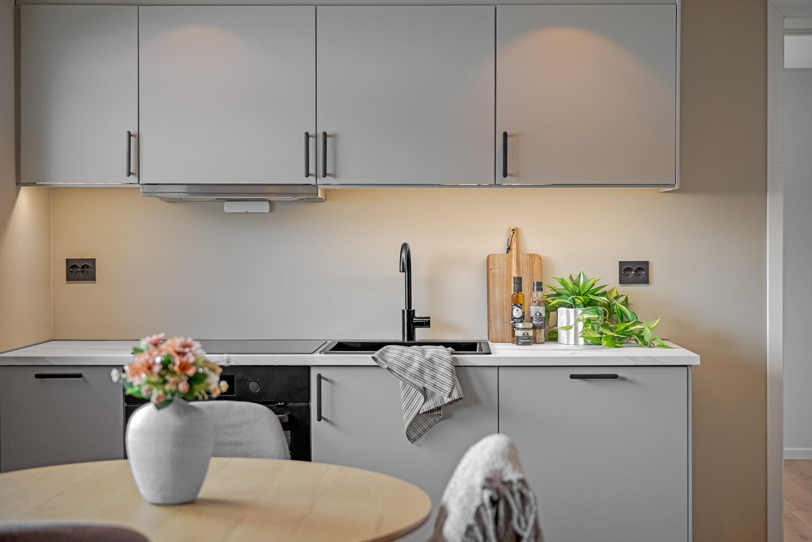 Stilrent kjøkken fra 2025 med glatte fronter og laminert benkeplate med nedfelt oppvaskkum. Kjøkkenet er utstyrt med integrerte hvitevarer som nedfelt platetopp, stekeovn og oppvaskmaskin. Galleribilde