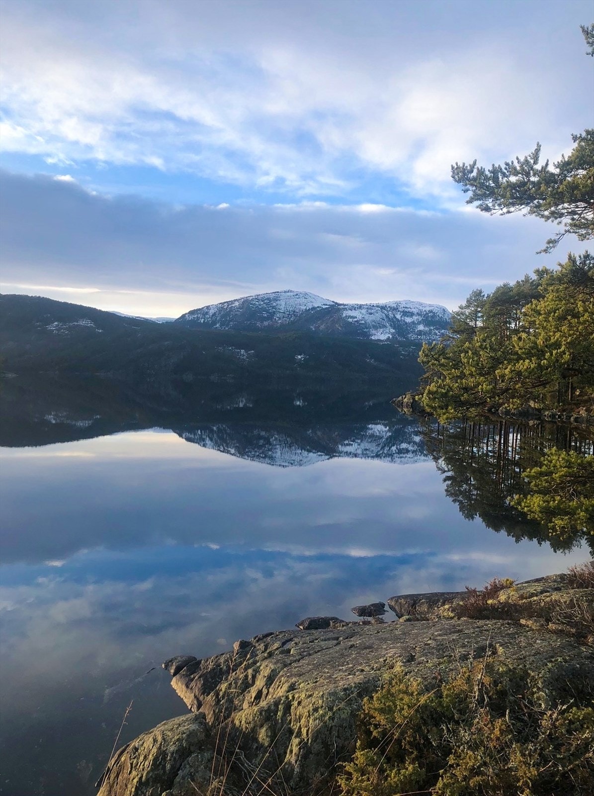 Fjellene speiler seg i det stille vannet, skaper en naturskjønn utsikt. Galleribilde