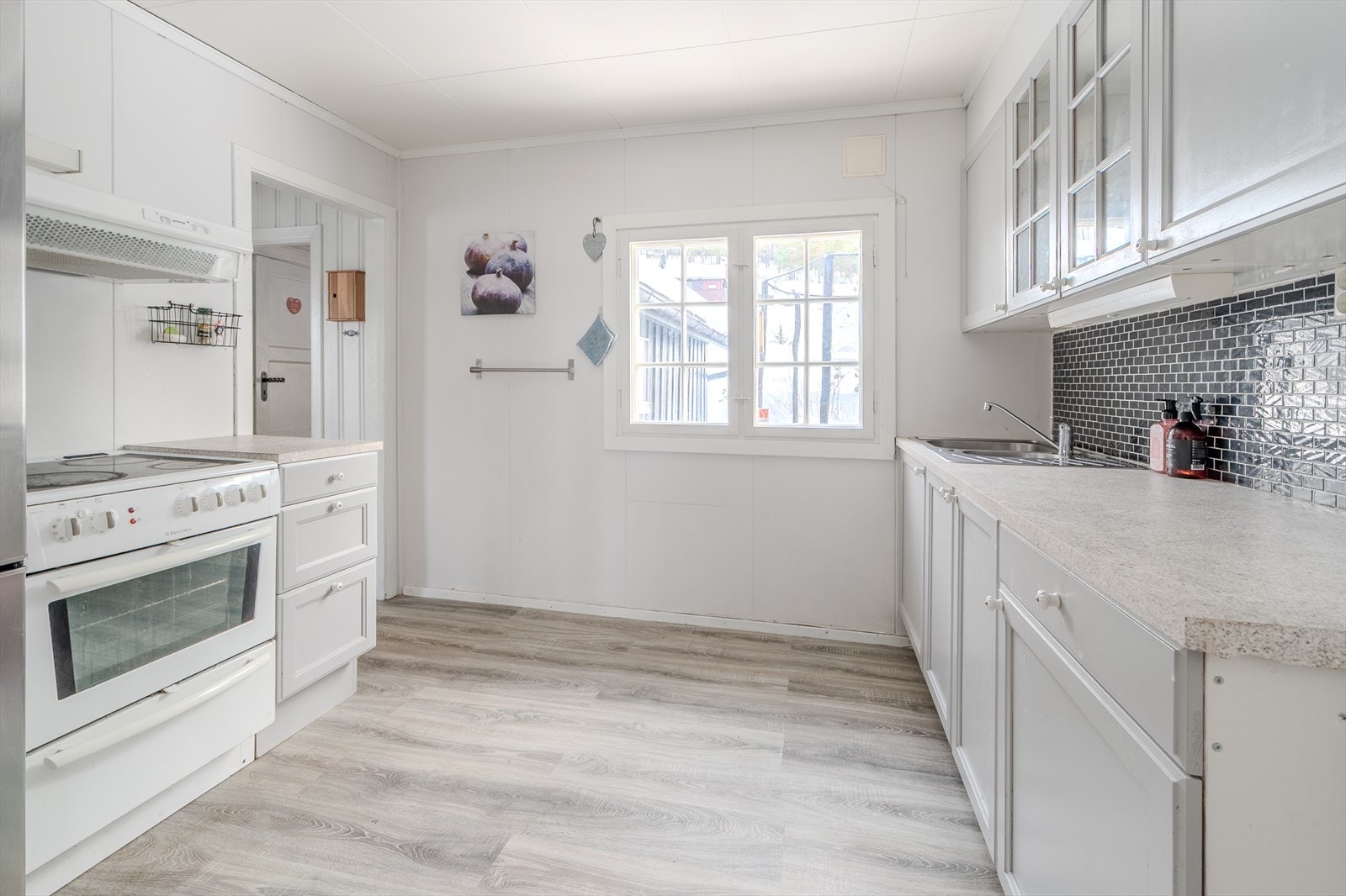 Innredning med malte fronter og laminert benkeplate gir praktisk arbeidsområde. Galleribilde