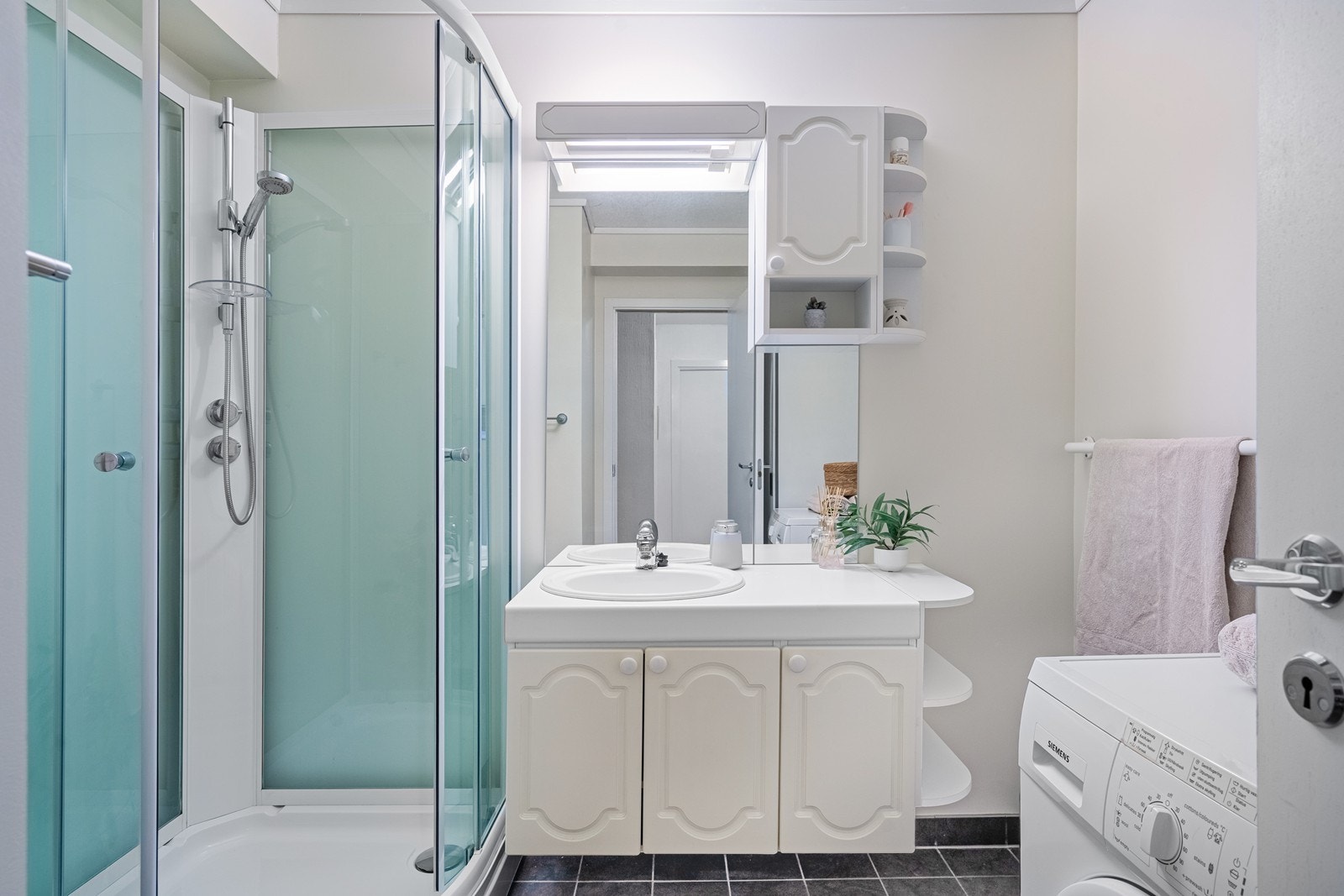 Lyst baderom med baderomsinnredning og dusjkabinett - fliser på gulv. Galleribilde